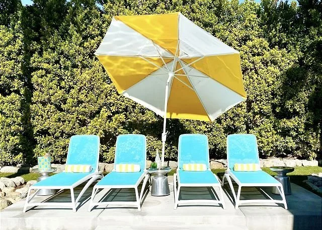 Turquoise pool loungers beneath a yellow-and-white parasol at Sunburst Palms.