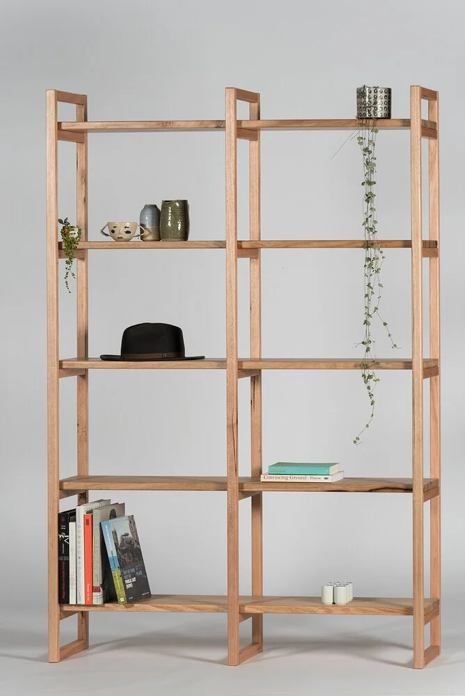 Tall open timber shelving displaying plants, books and decorative objects.