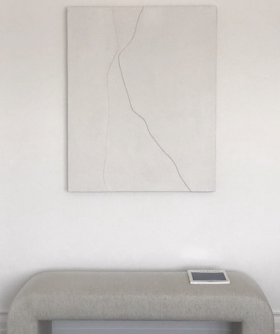 Minimal white artwork with an abstract line above an arched upholstered bench.