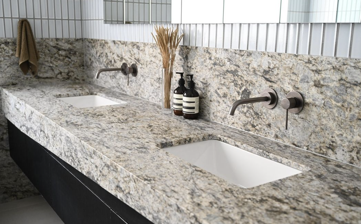 Double stone vanity with inset white basins, black taps and dark cabinetry.