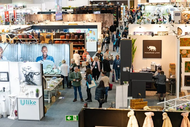 Visitors browsing furniture and homewares displays at a design trade fair.