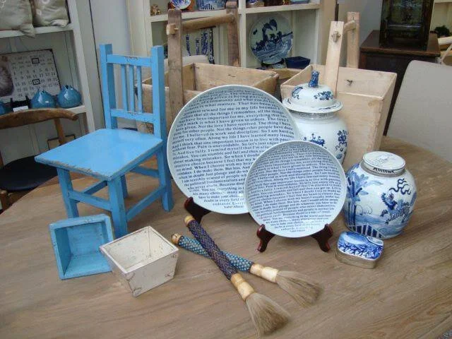 Blue chair displayed with blue-and-white porcelain platters and vases.