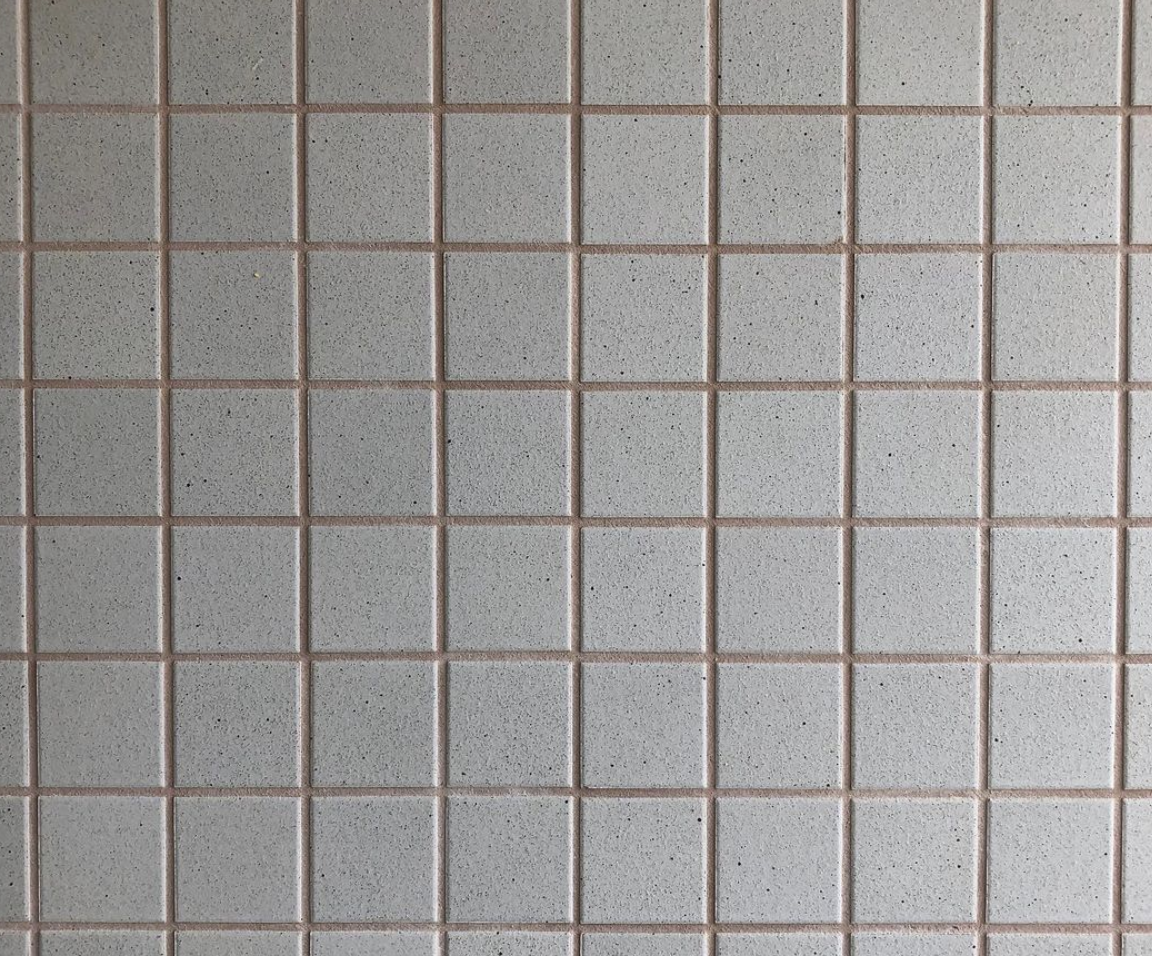 Square pale grey wall tiles with contrasting grout lines.
