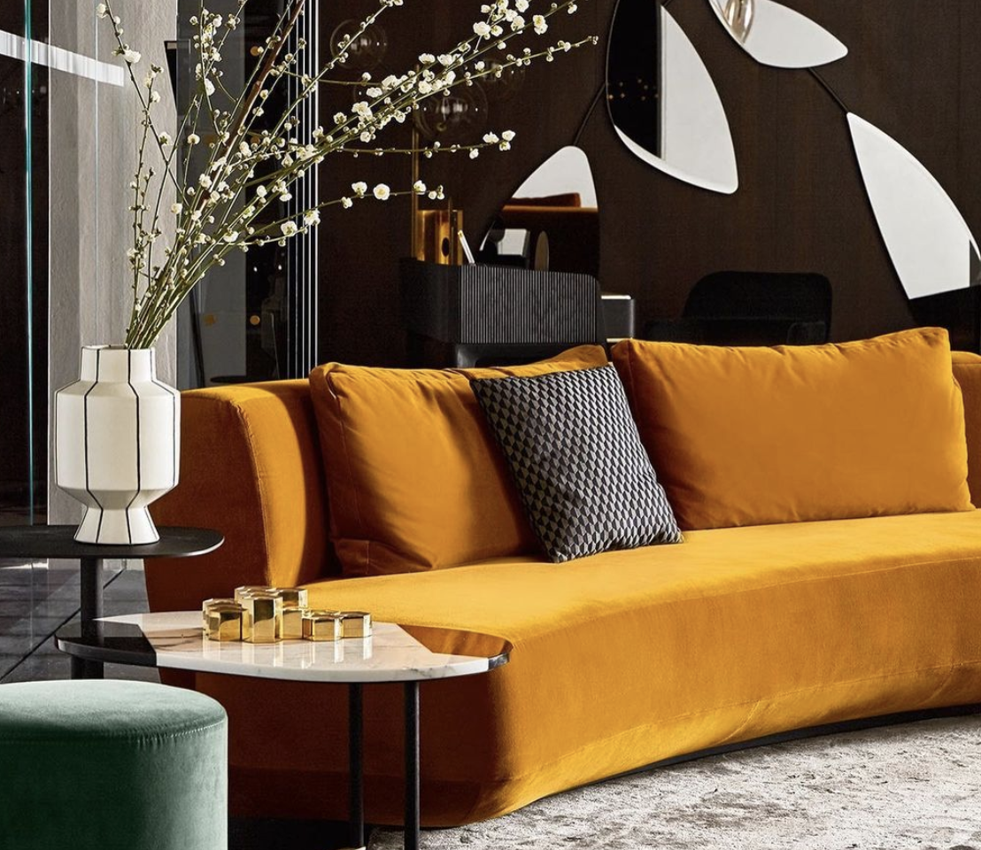 Mustard sofa beneath graphic black-and-white wall art in a dark-toned living room.