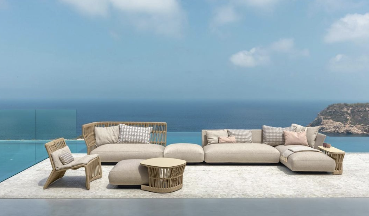 Pale outdoor modular seating and a low table on an ocean-view terrace.