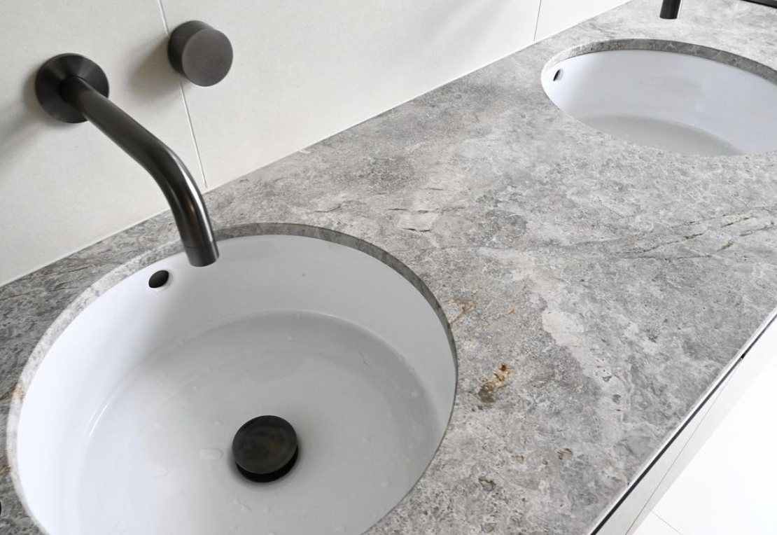 Grey stone vanity with two white inset basins and black wall-mounted taps.