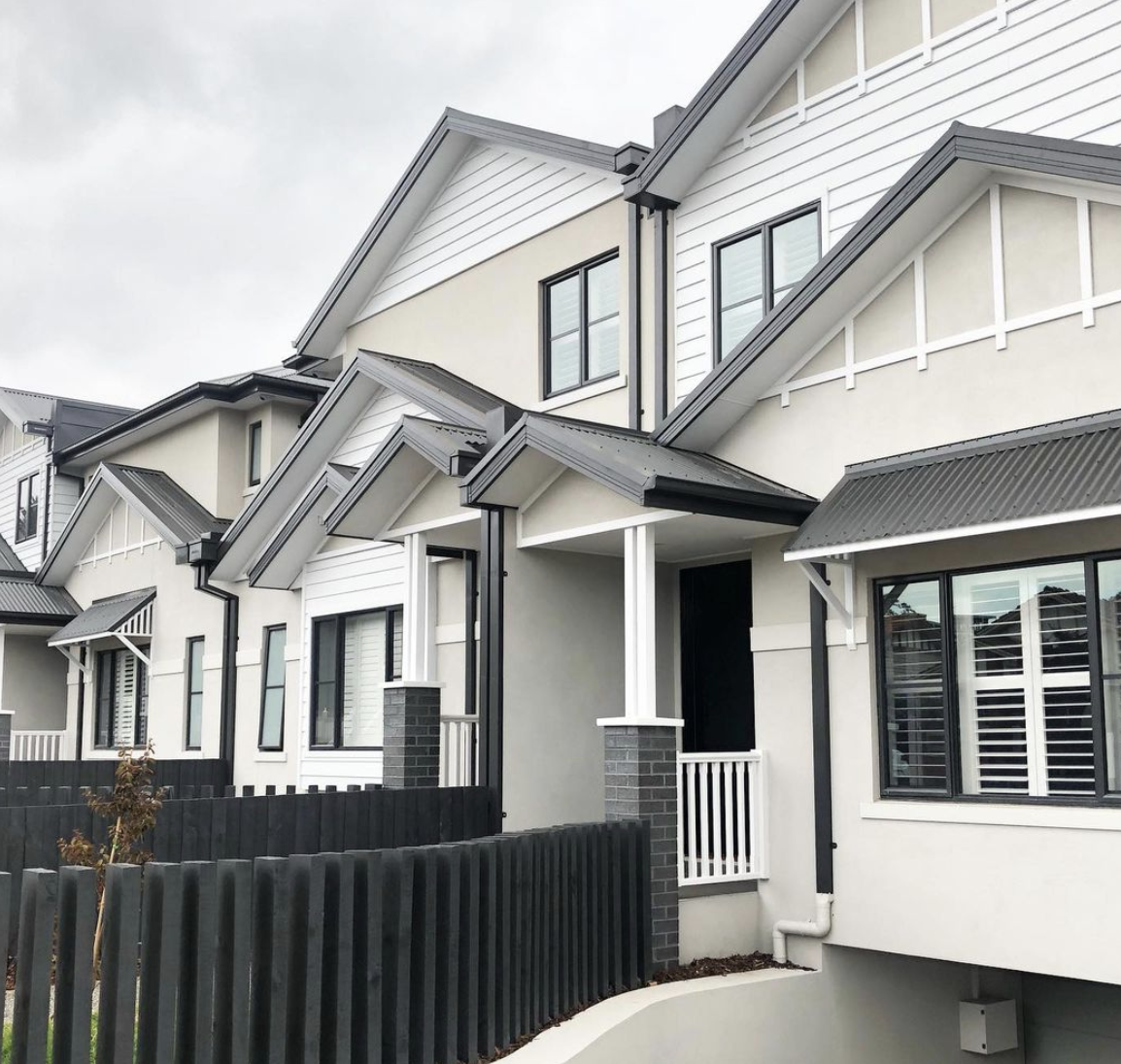 Weatherboard houses with pitched roofs, porches and black picket fencing.