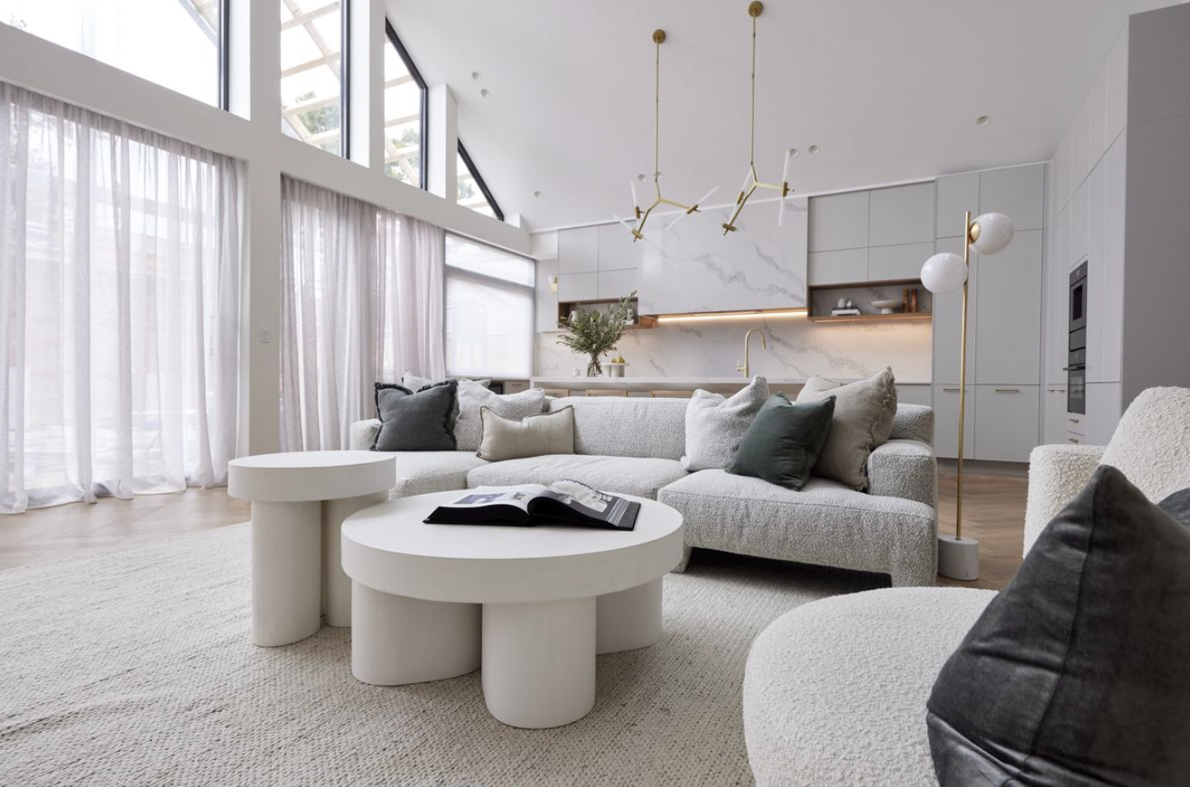 Light-filled living room with curved sofas, pale upholstery and low rounded coffee tables.