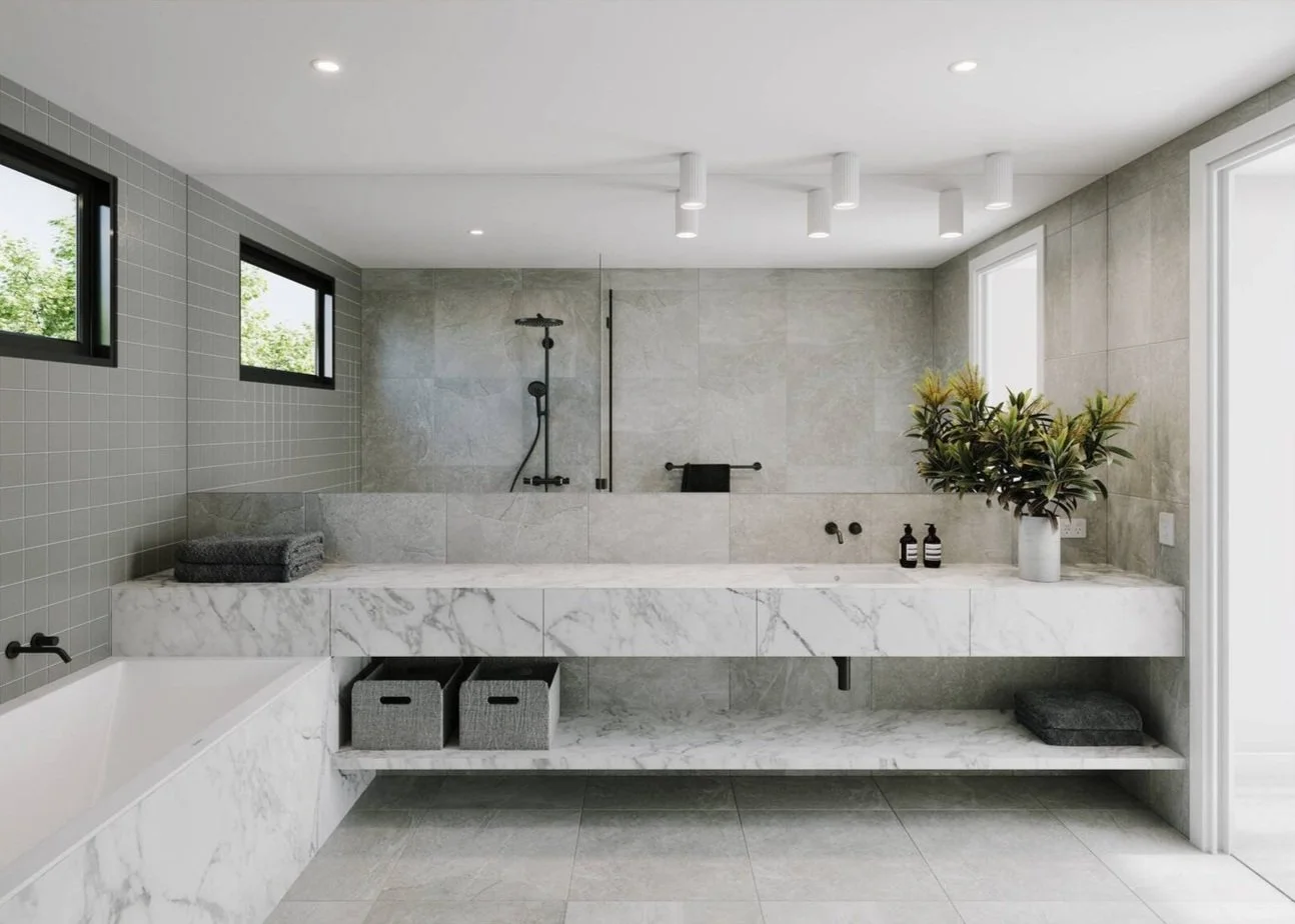 Modern bathroom with a marble bathtub, gray tiles, and a plant on the right side. The background features a shower area with black fixtures and a frosted glass privacy partition. The ceiling has recessed lighting.