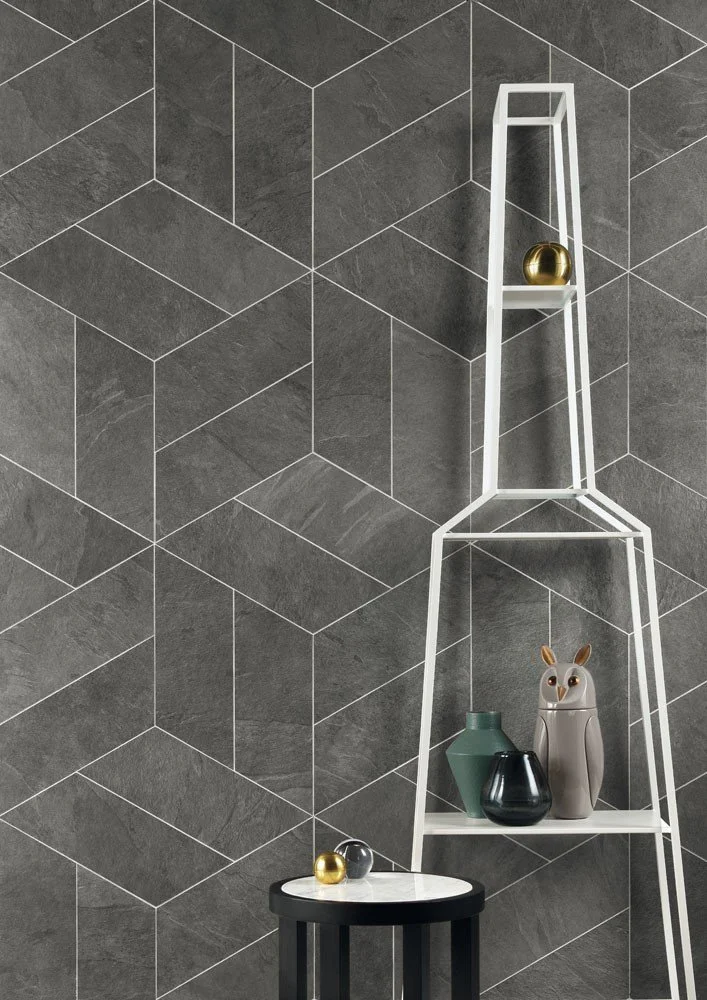 Tall sculptural bottle-shaped shelving unit against geometric dark tiles.