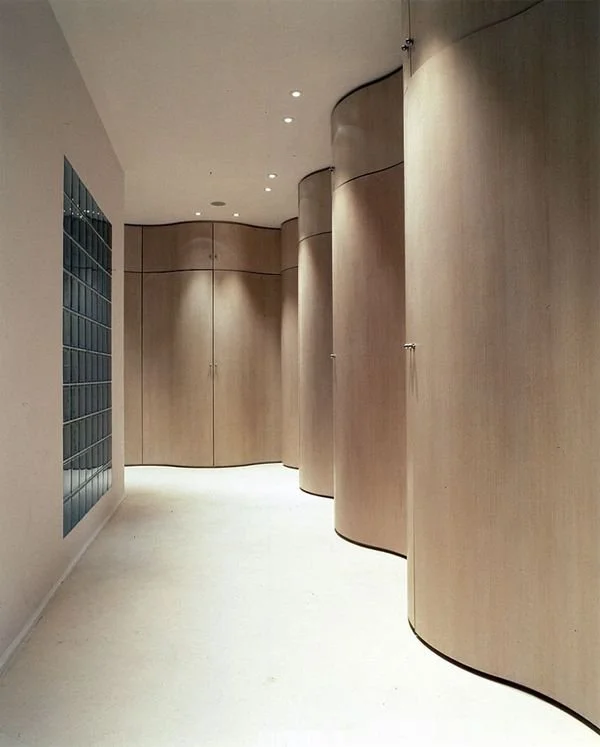 Curved timber wall and doors along a softly lit corridor.