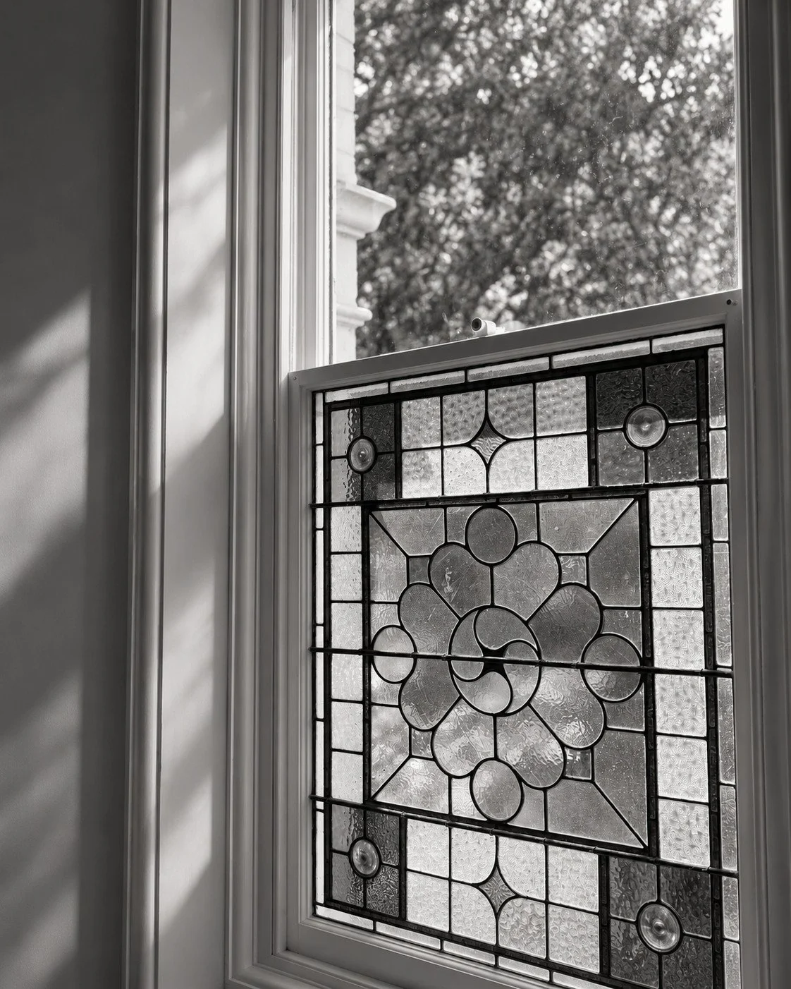 Craigneal leadlight window detail overlooking established garden trees.