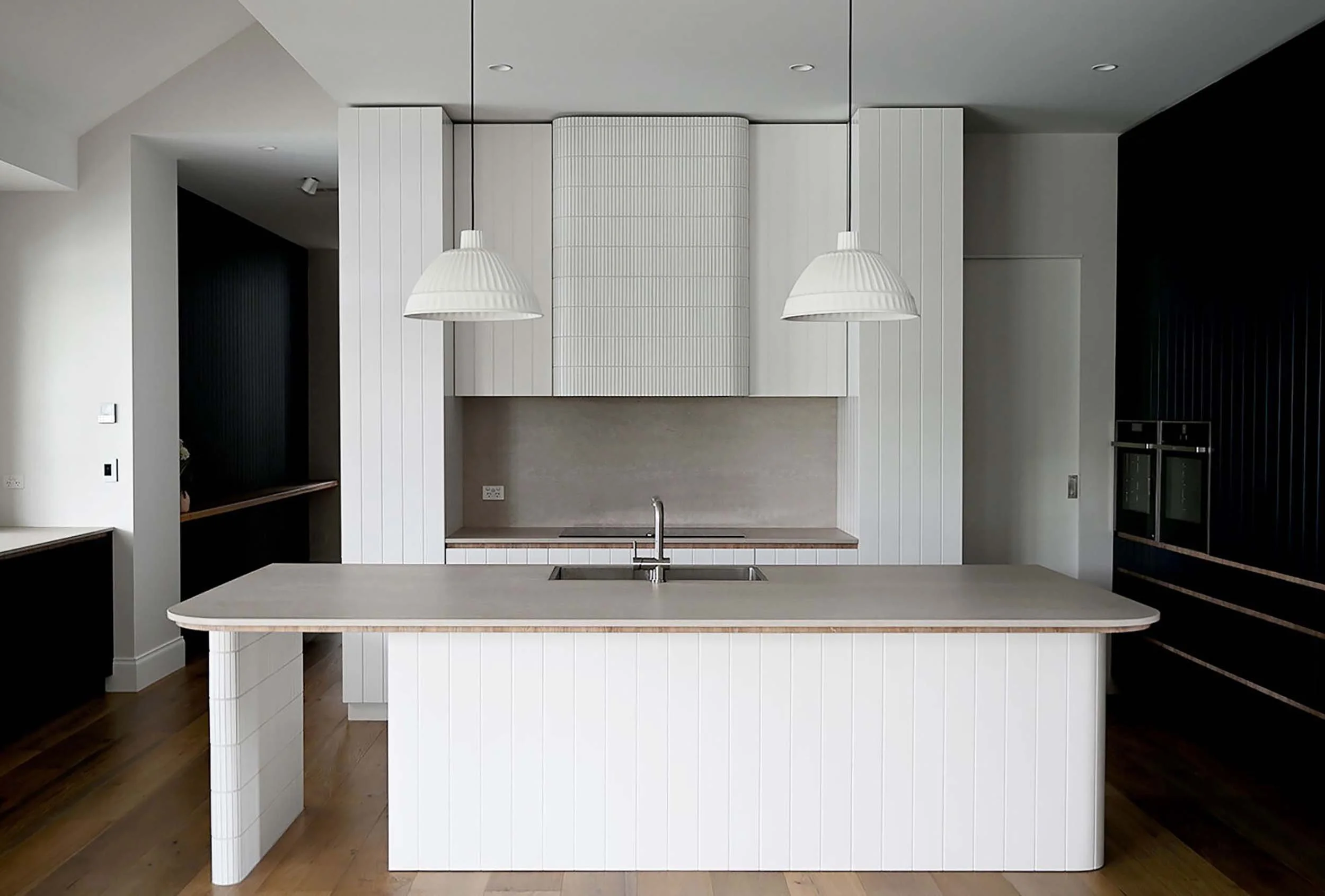 Modern kitchen with white island, pendant lights, and built-in cabinetry.