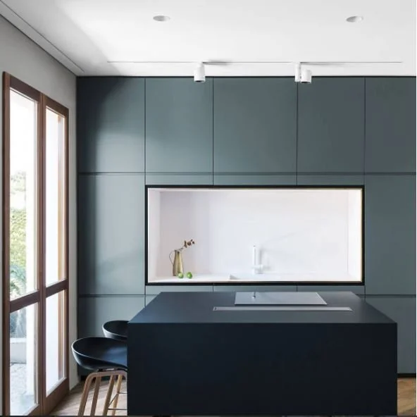 Dark green cabinetry framing a recessed pale splashback and low island.