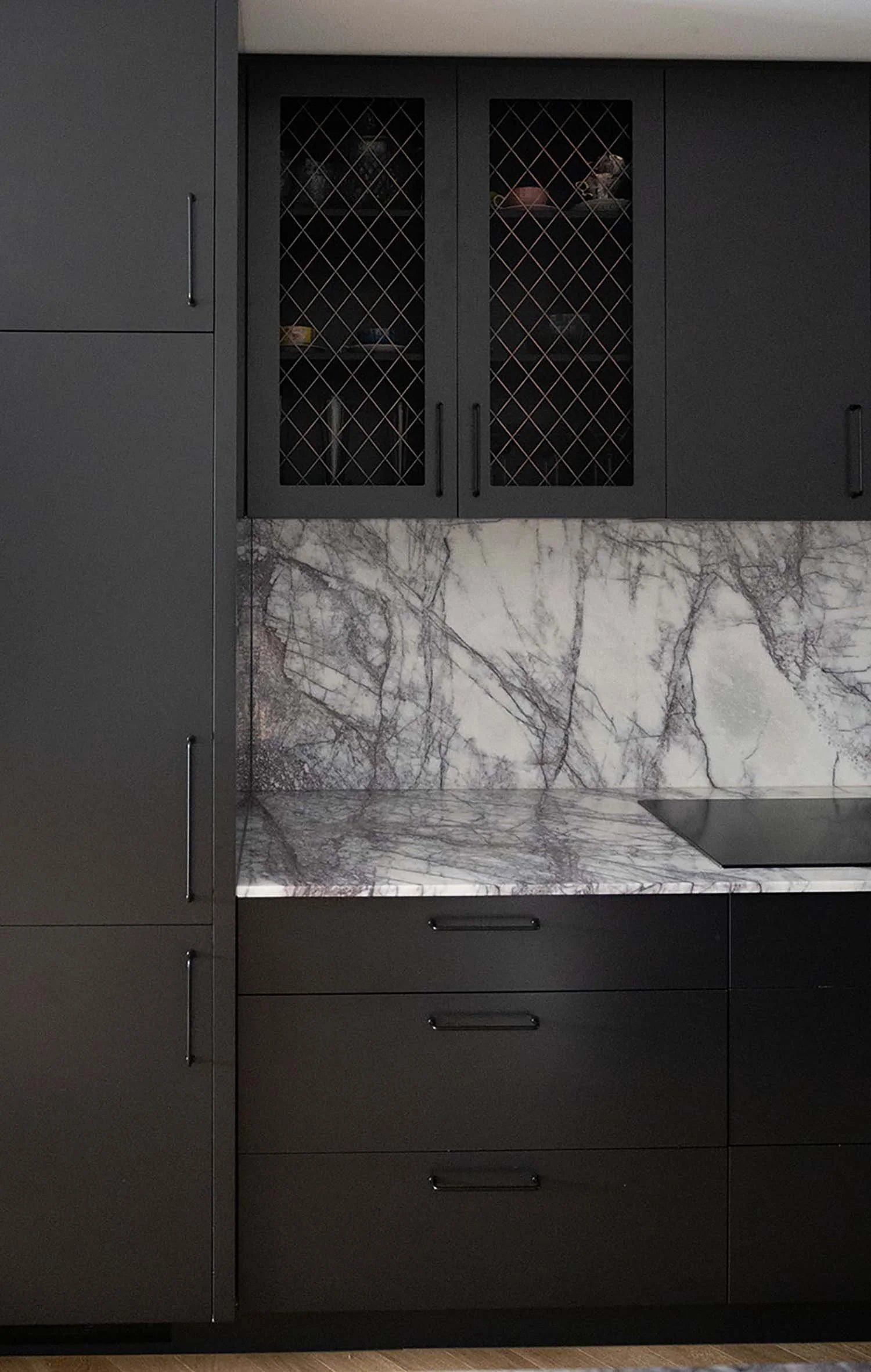 A kitchen with dark gray cabinets, a marble backsplash with gray and white veins, and a marble countertop with a gray and white pattern.