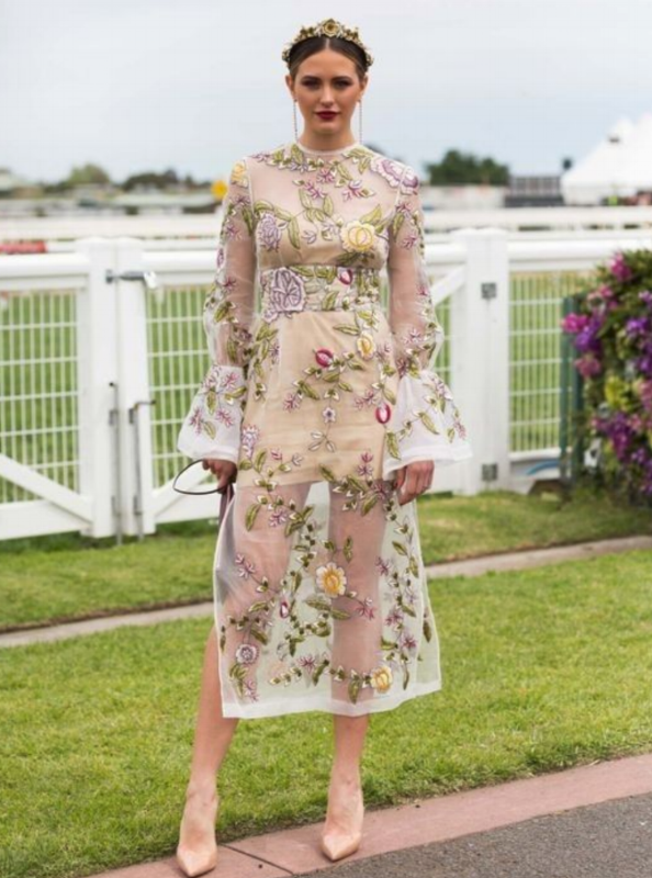 Model wearing a pale floral dress in an outdoor setting.