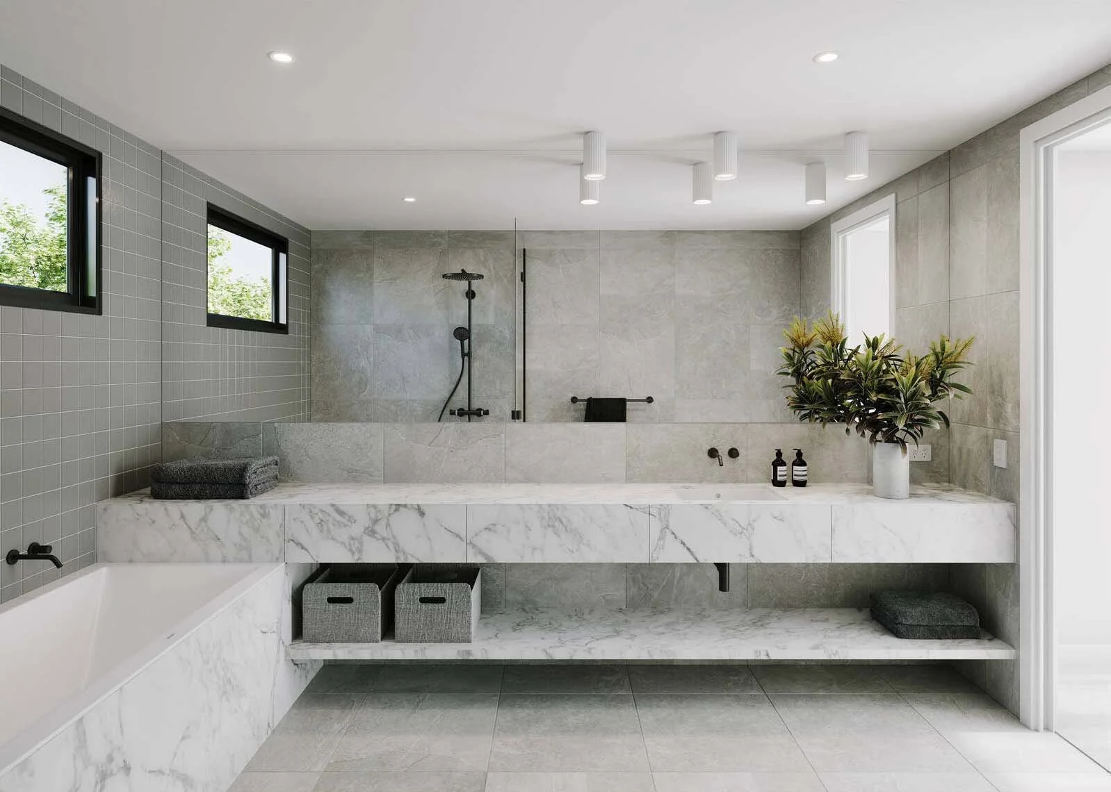 Modern bathroom with marble and gray tiles, a bathtub, and a walk-in shower with black fixtures. There are two small windows, a potted plant, coutstered bottles, and baskets under the marble countertop.