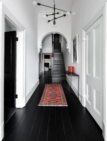 Light hallway with dark timber flooring and an arched doorway.