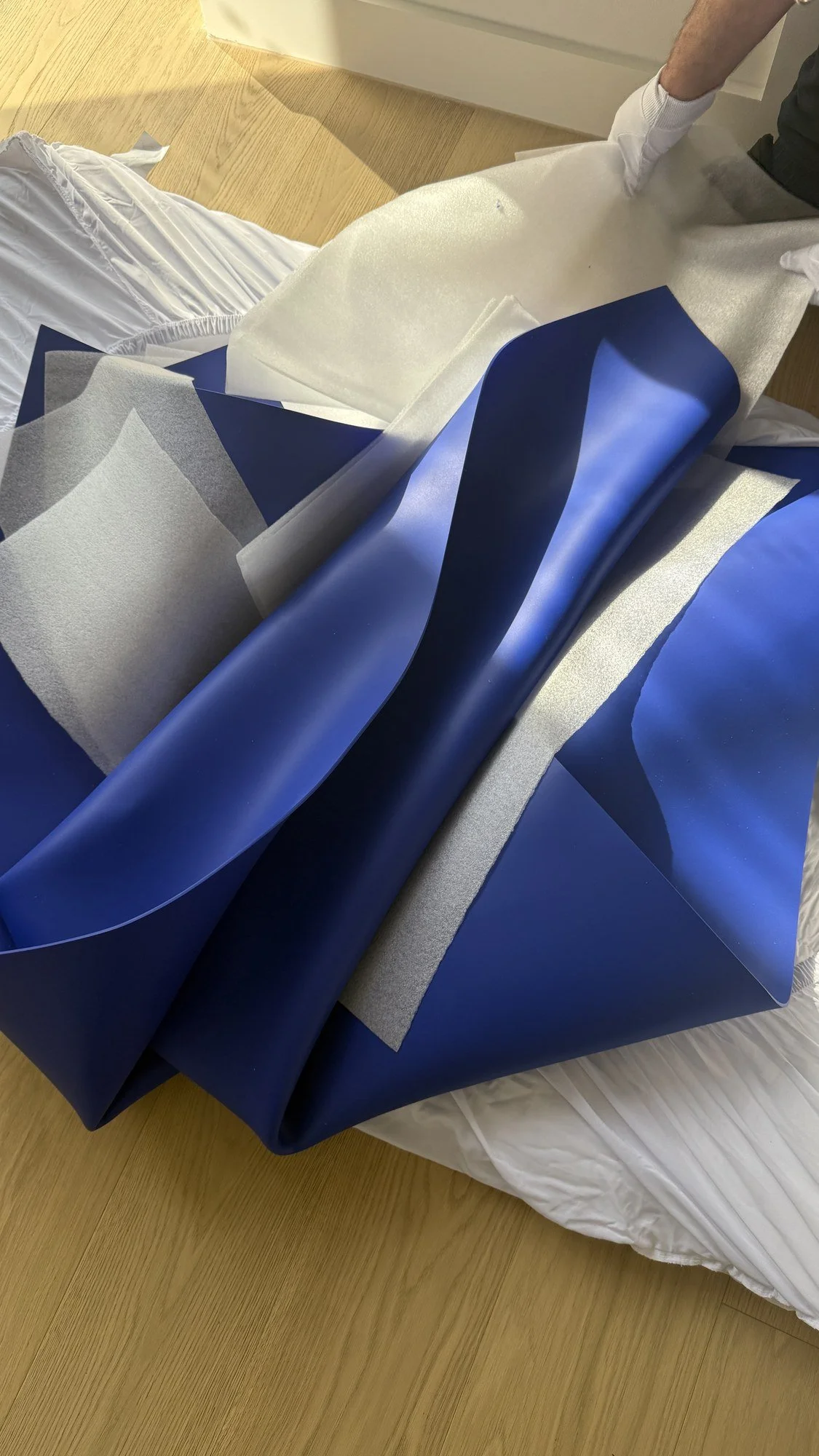 A large blue artwork being unwrapped and positioned within an interior.
