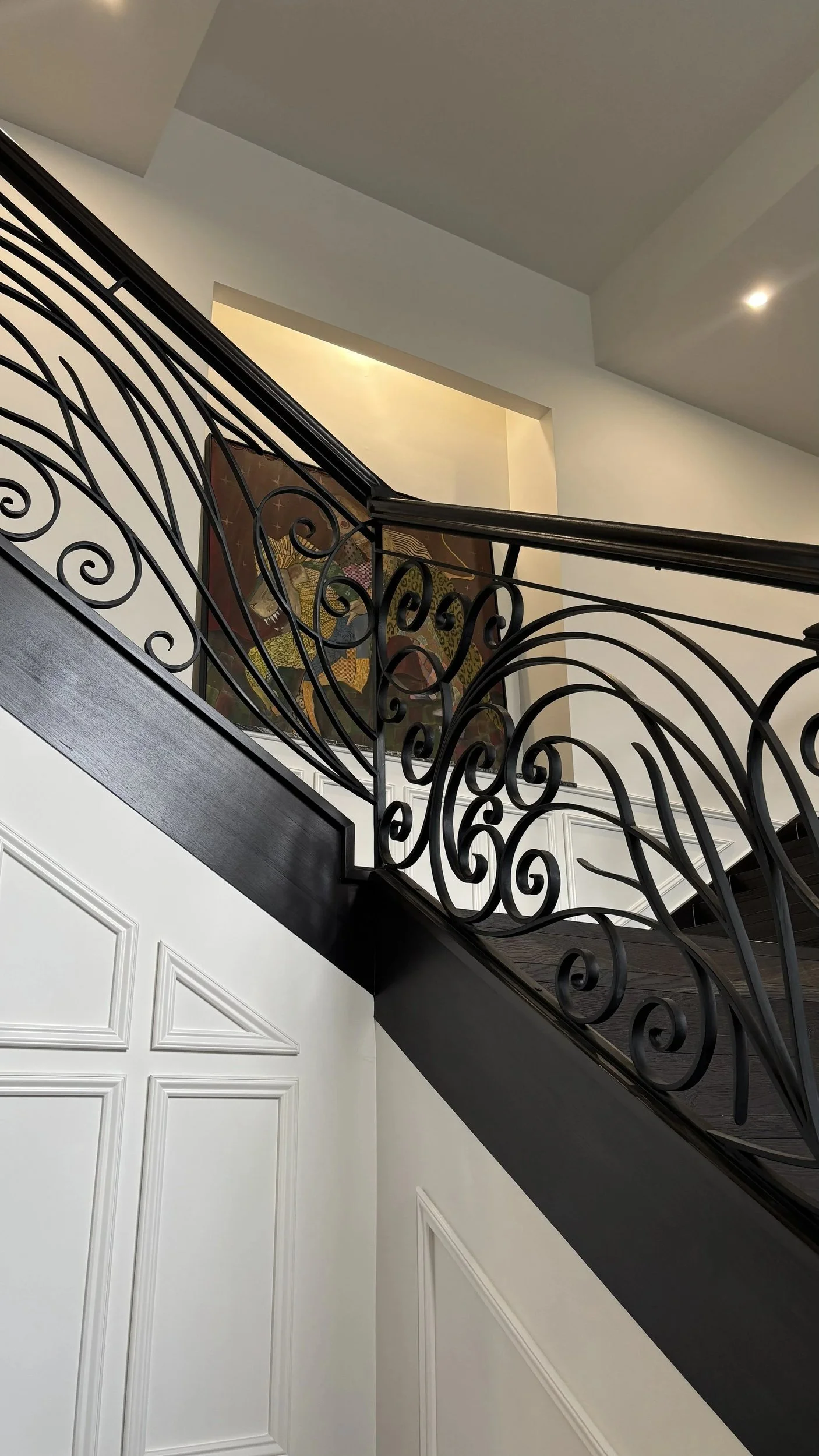 Decorative dark metal staircase balustrade with flowing curved motifs.
