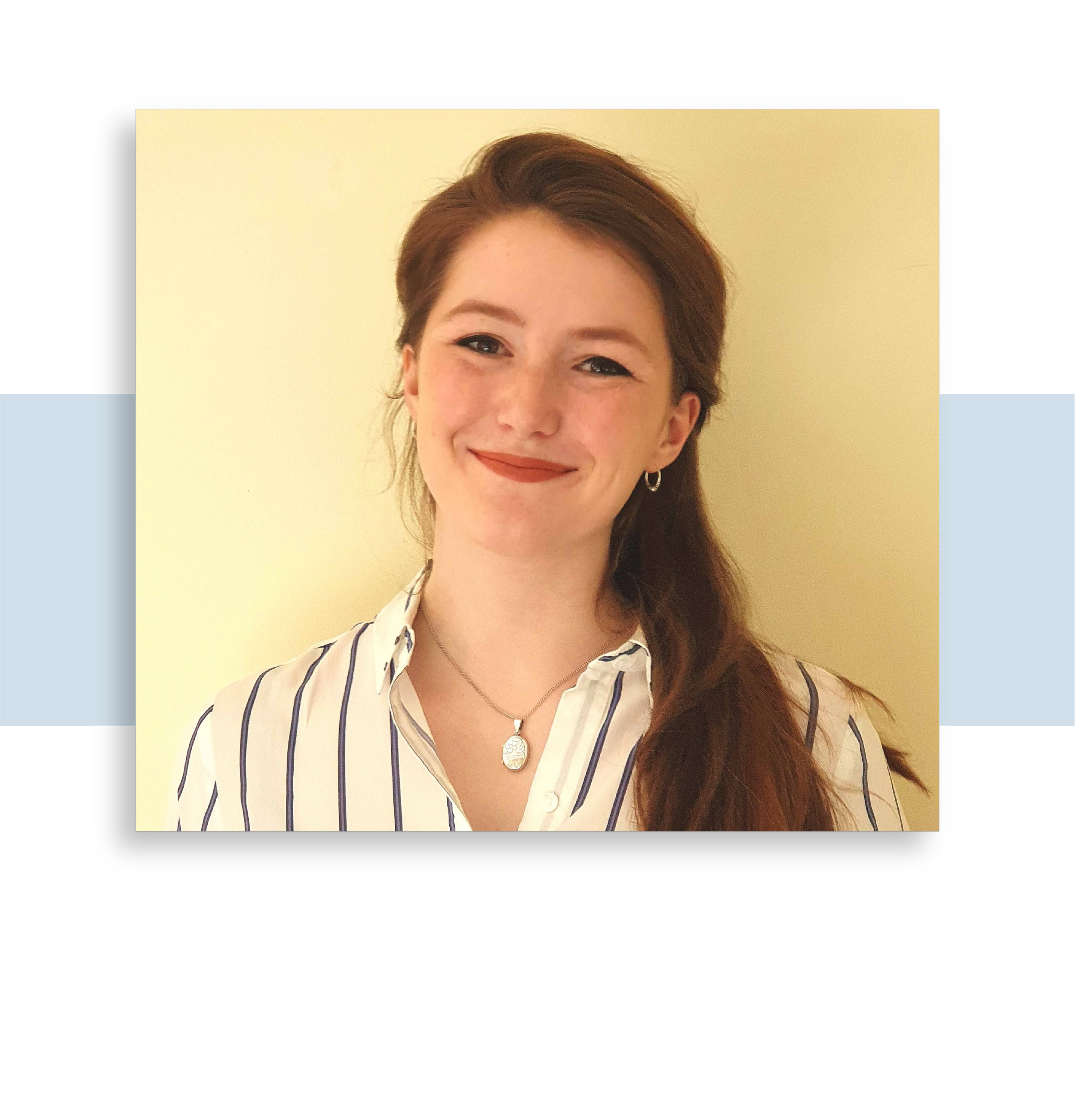 Image of Dr. Emily Green. Portrait of a smiling woman with red hair, wearing a striped white shirt, standing against a plain light-colored background.