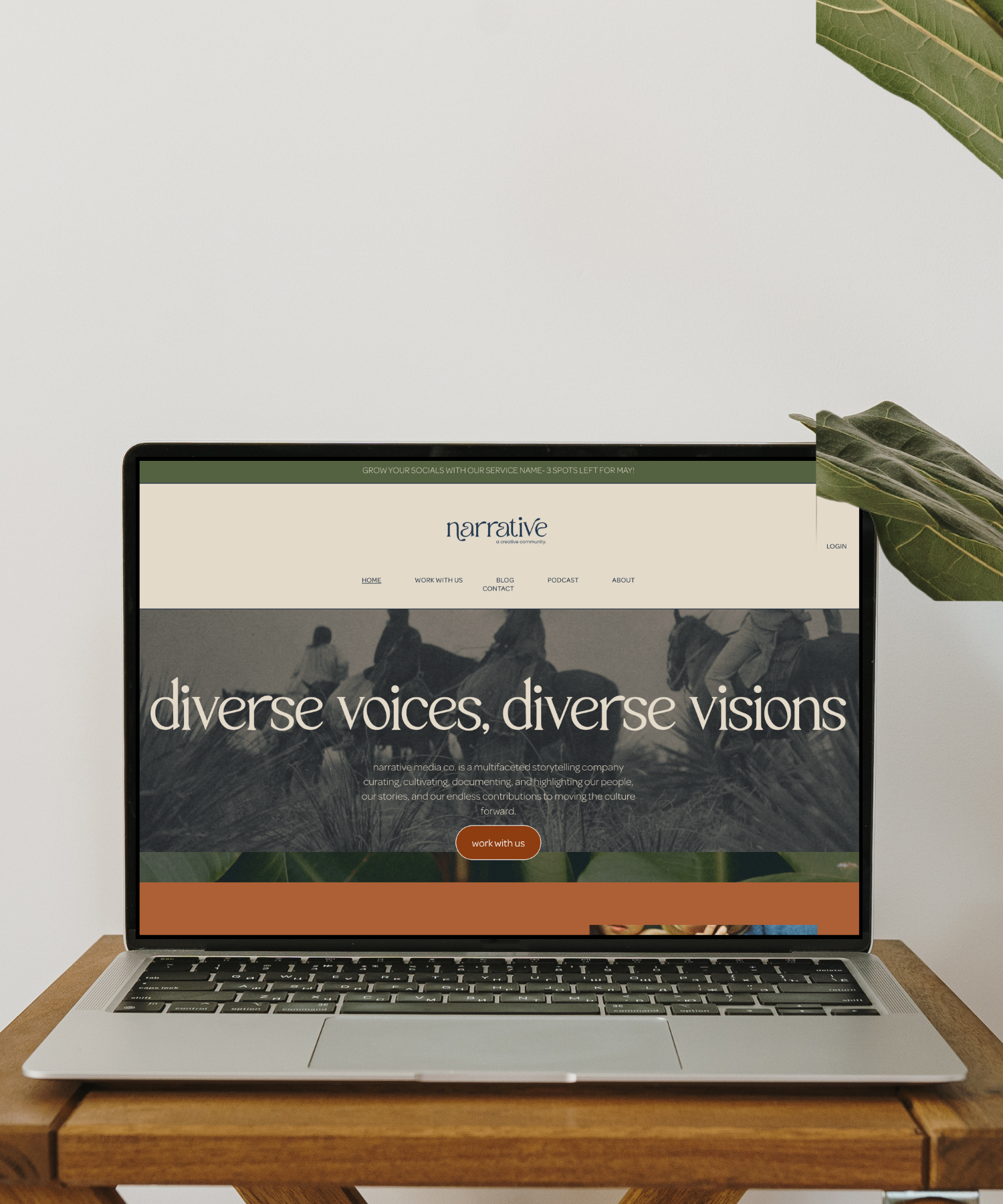 Laptop displaying a website titled "Diverse voices, diverse visions" on a wooden table with green leaves in the background.