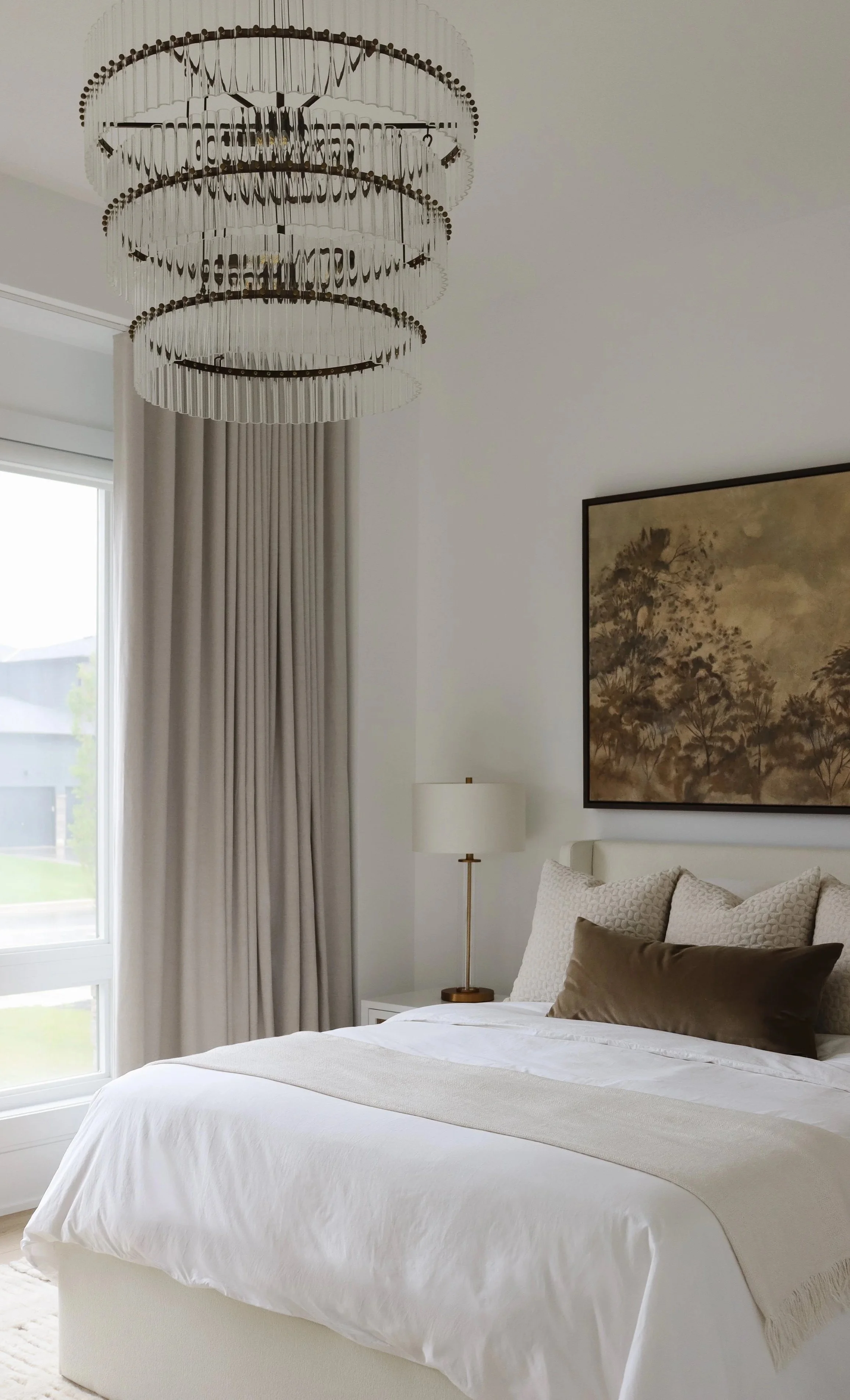 Calm neutral bedroom with a glass chandelier, linen drapery and a landscape painting, designed by Leah Simpson