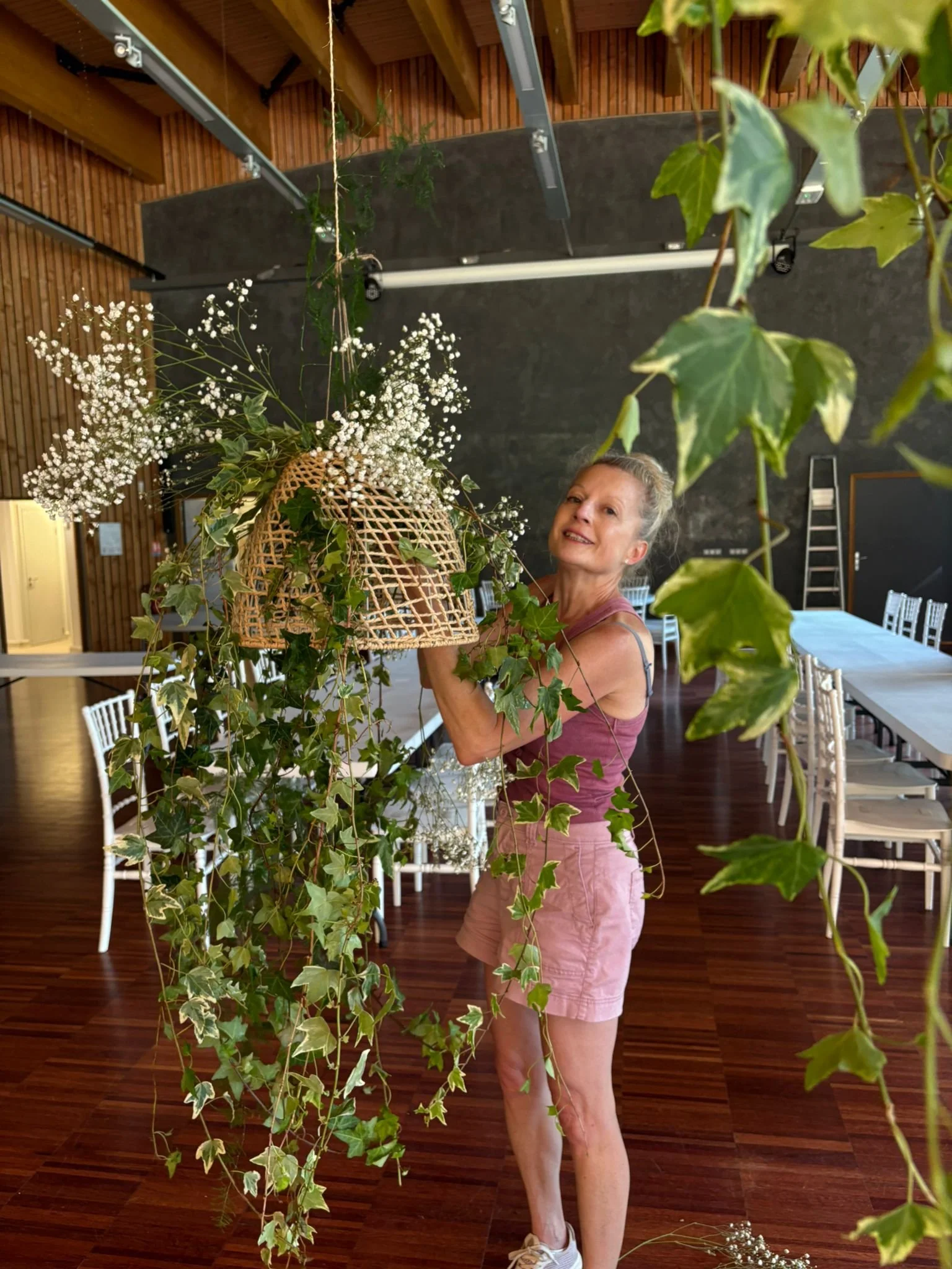 wedding florist preparing greenery into baskets for a ceiling installation at the wedding venue