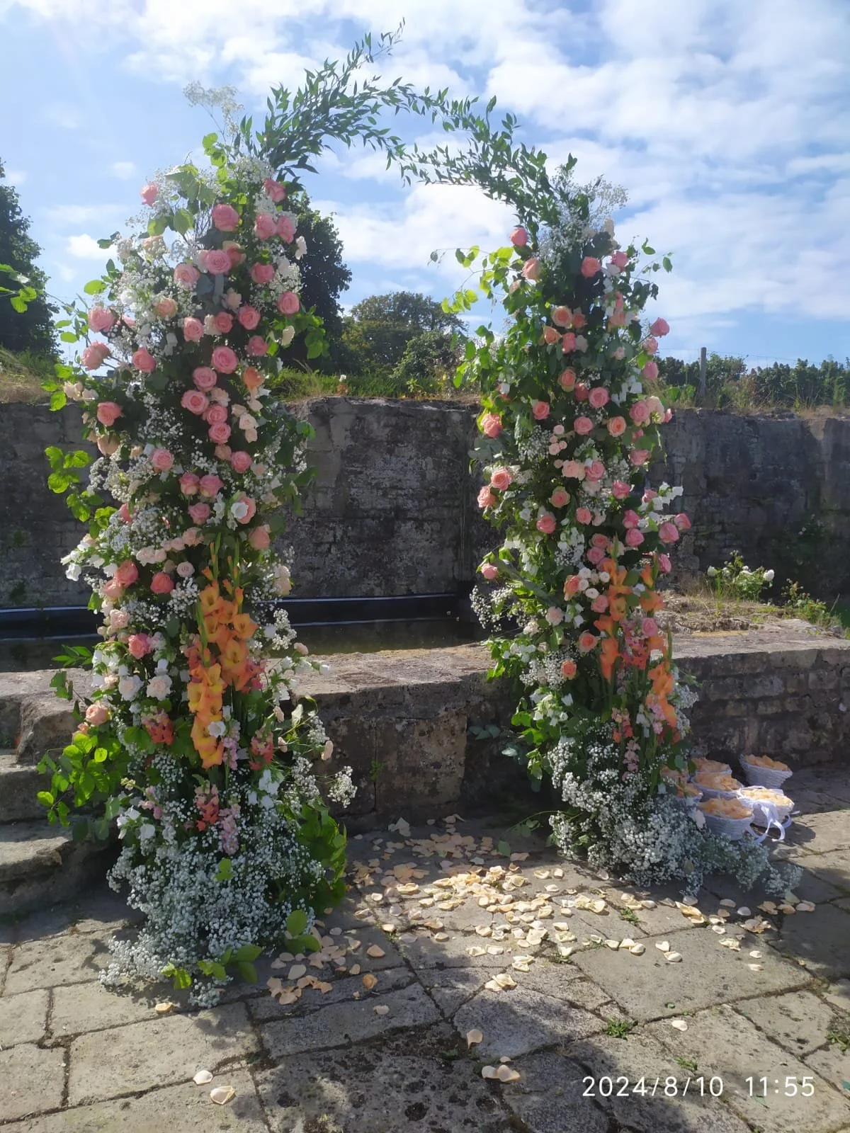 Abundant flowers against a blue sky fill this wedding arch for a destination wedding in France