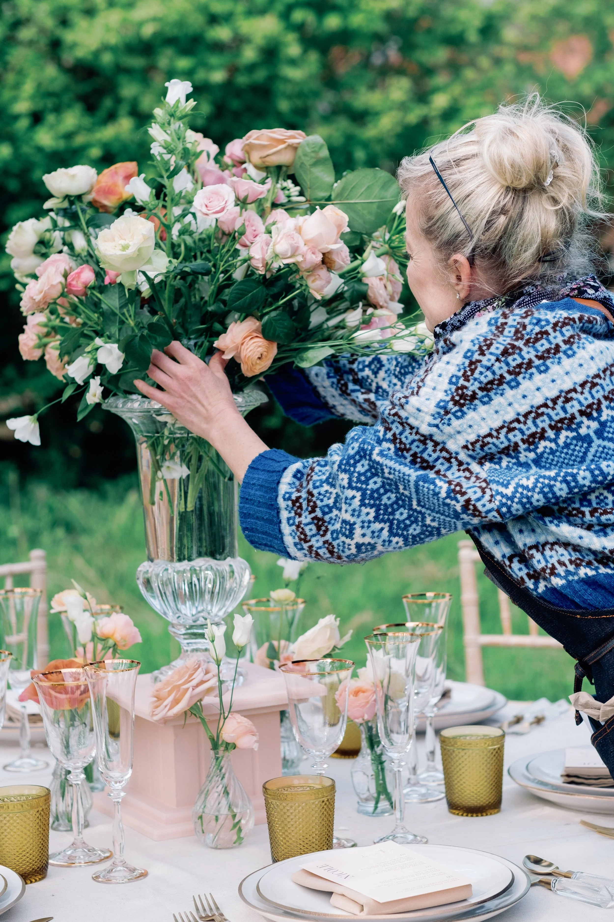 woman florist reaching to arrange flowers on a wedding dinner table in France
