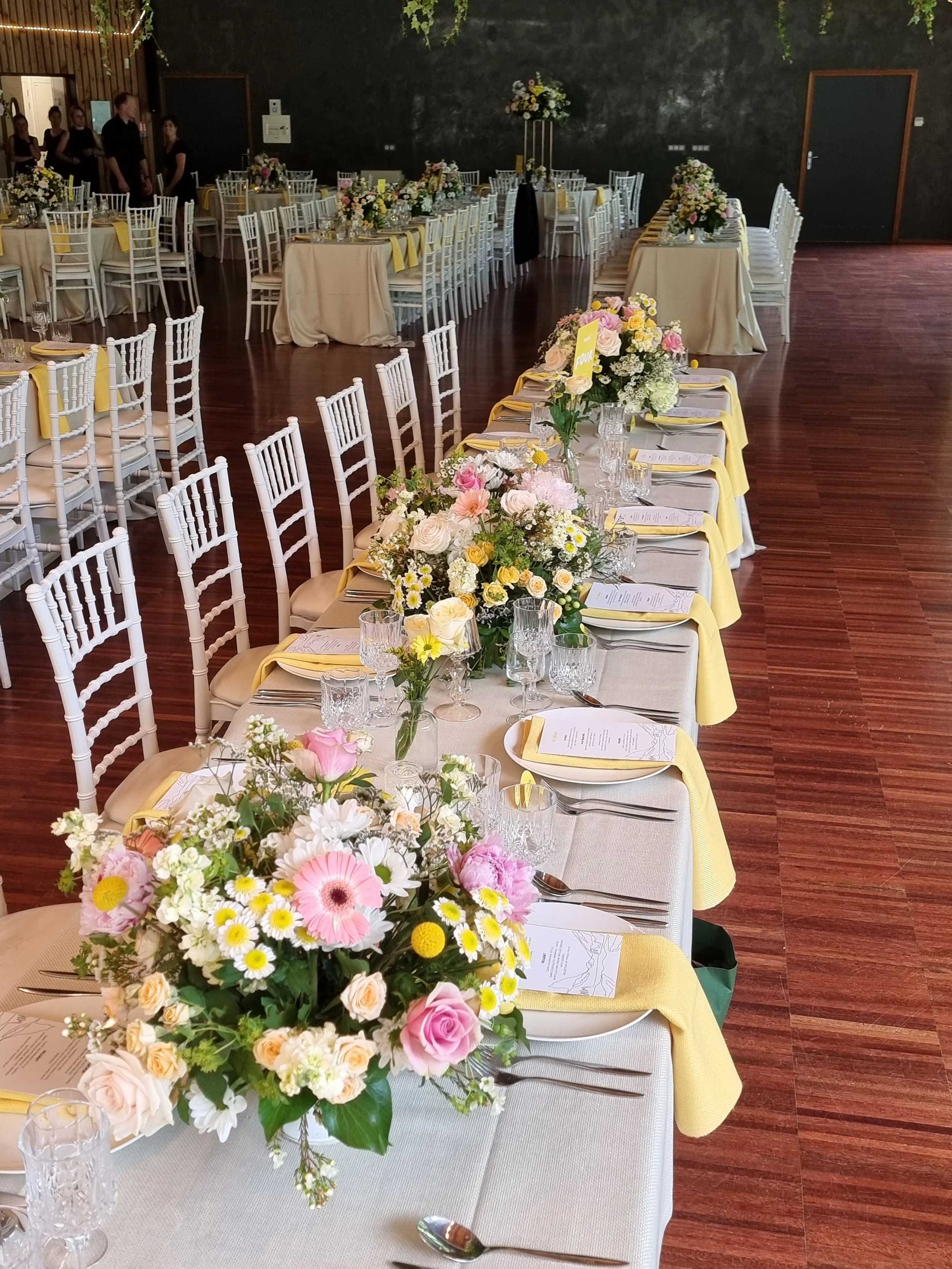 wedding flowers fill tables with different heights to fill the space of the room at a venue in France