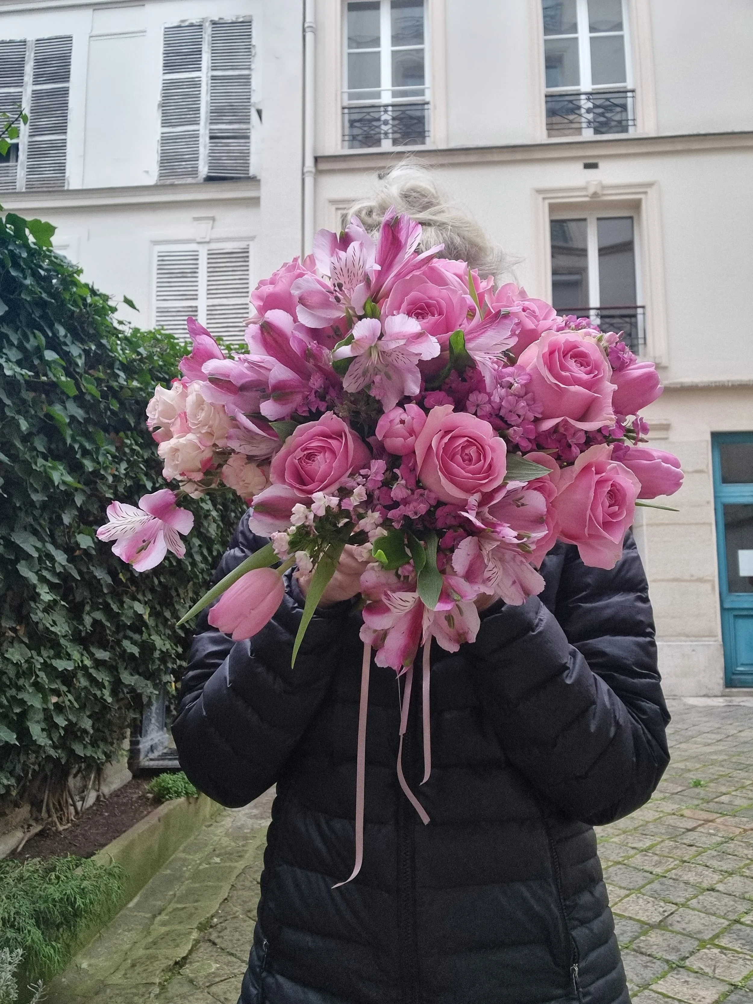 woman hides her face behind a bridal bouquet in pink for a destination wedding in france