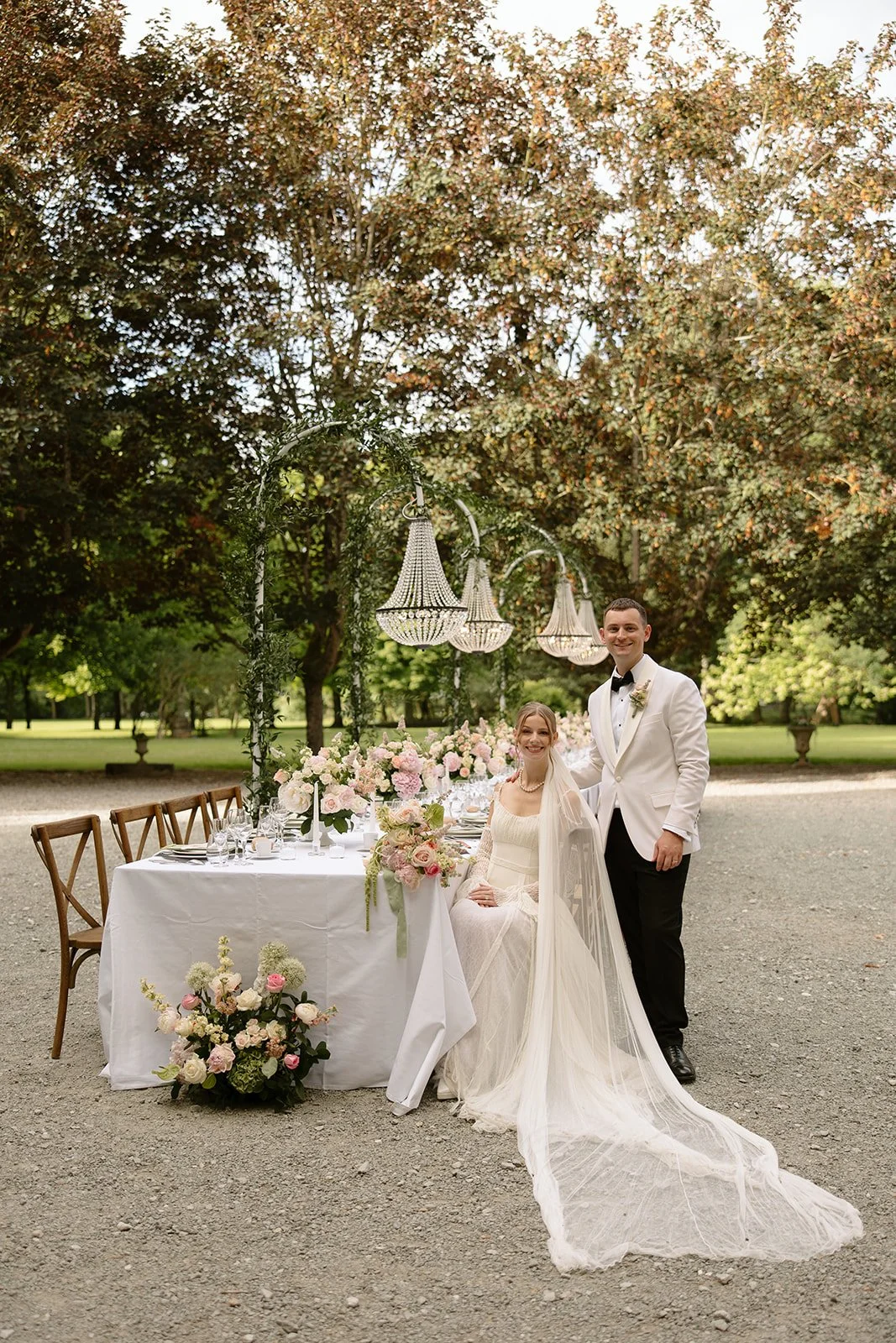 wedding couple in front of their reception table with wedding flowers at a chateau in france Chateau Allure du Lac