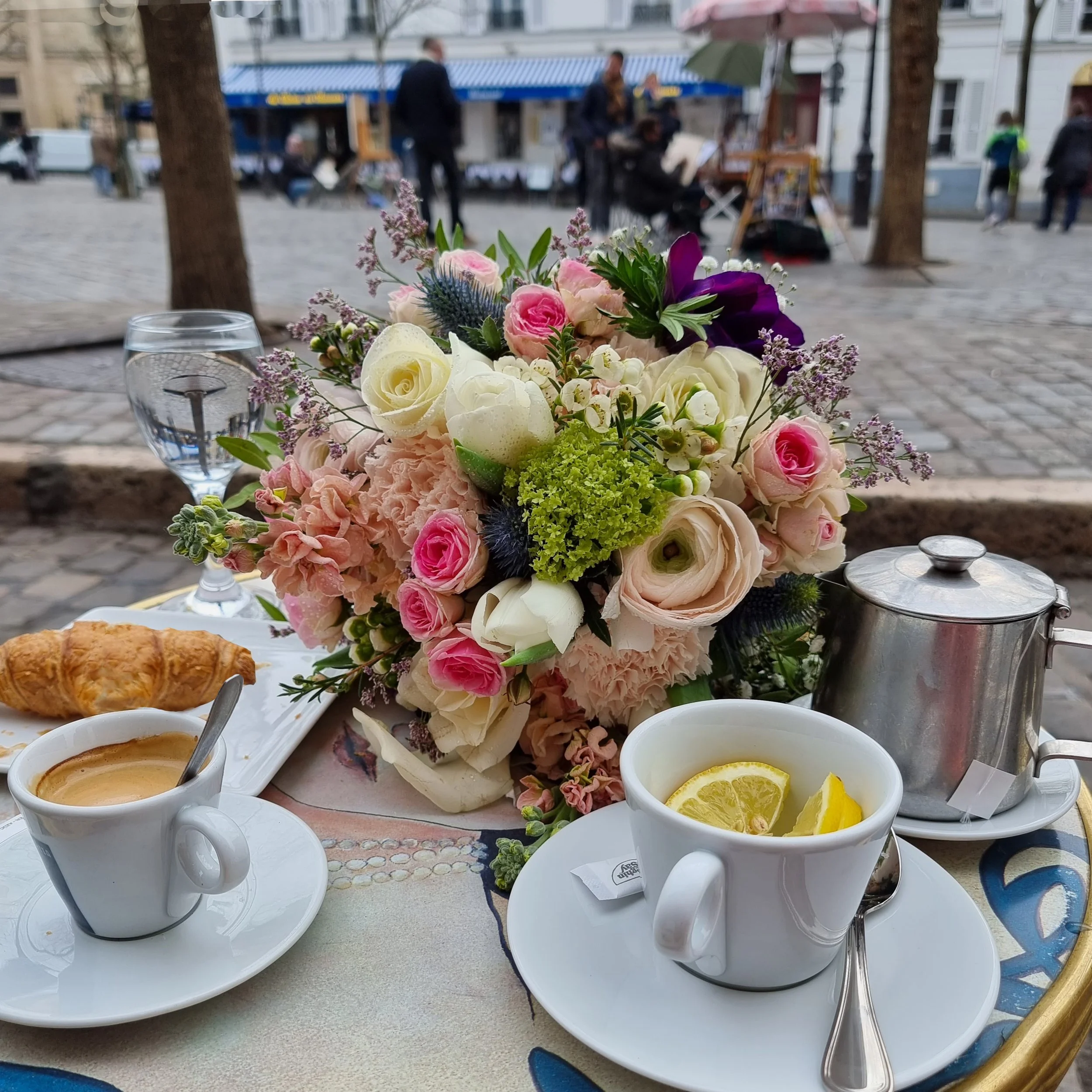 a floral bouquet sits on a table in front of artists in Paris Montmartre