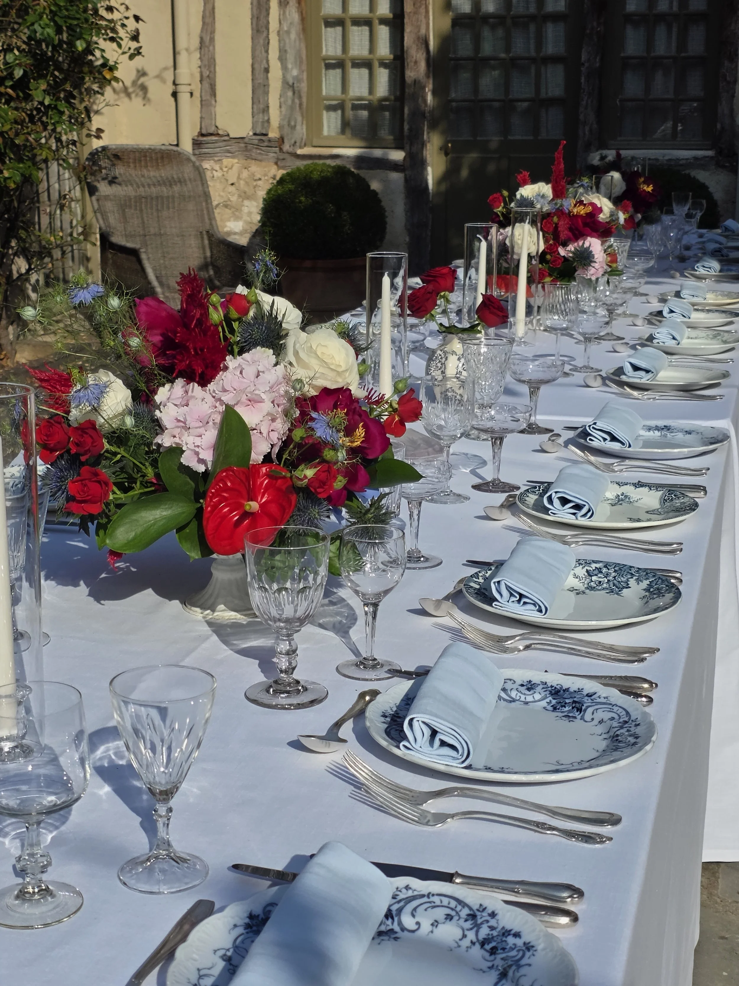 Dinner was served on French blue chinaware and bouquets lined the table with a small chinaware blue and white vase with large red roses.