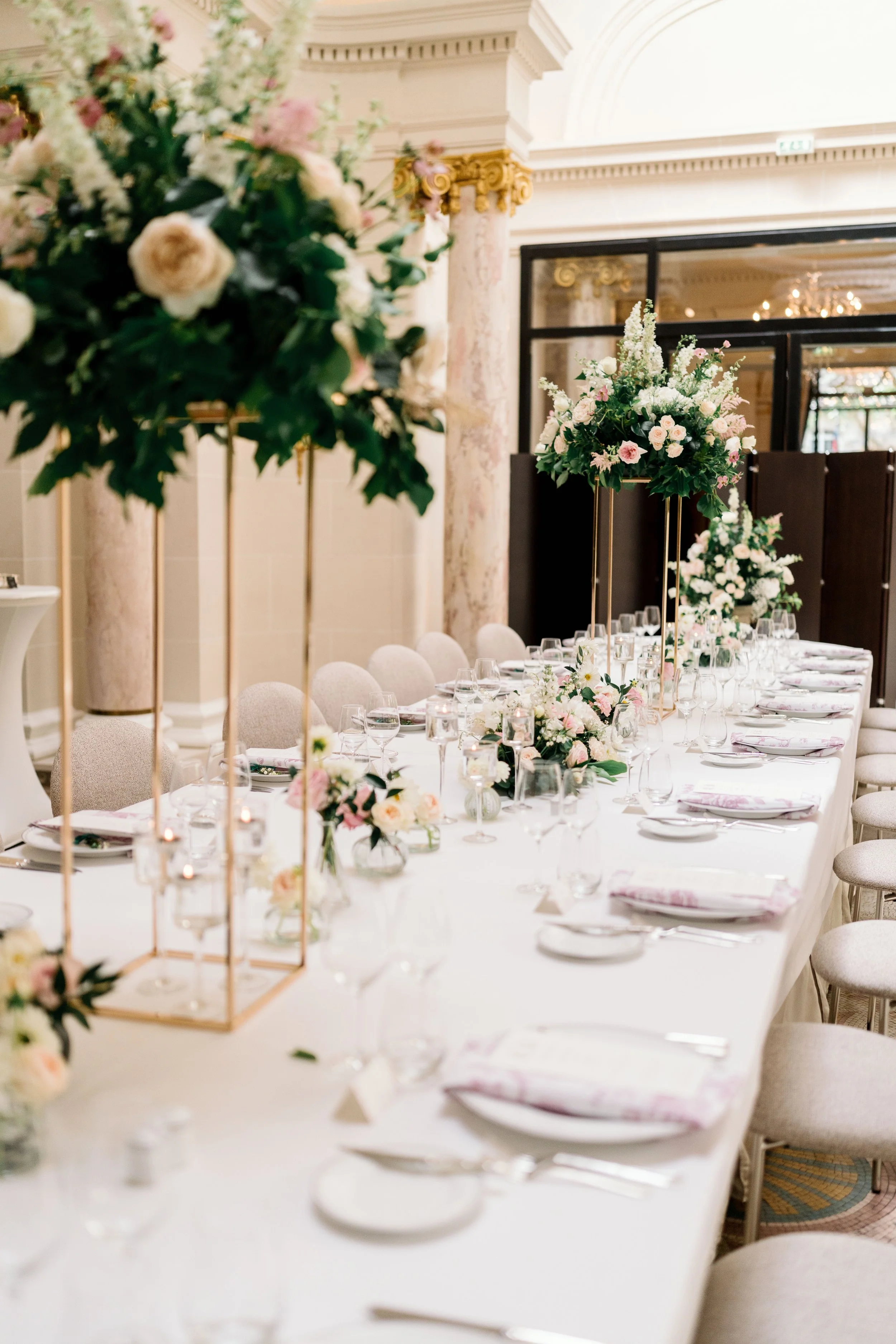 Wedding table with tall floral arrangements sit on an elegant paris hotel table for a destination wedding in france