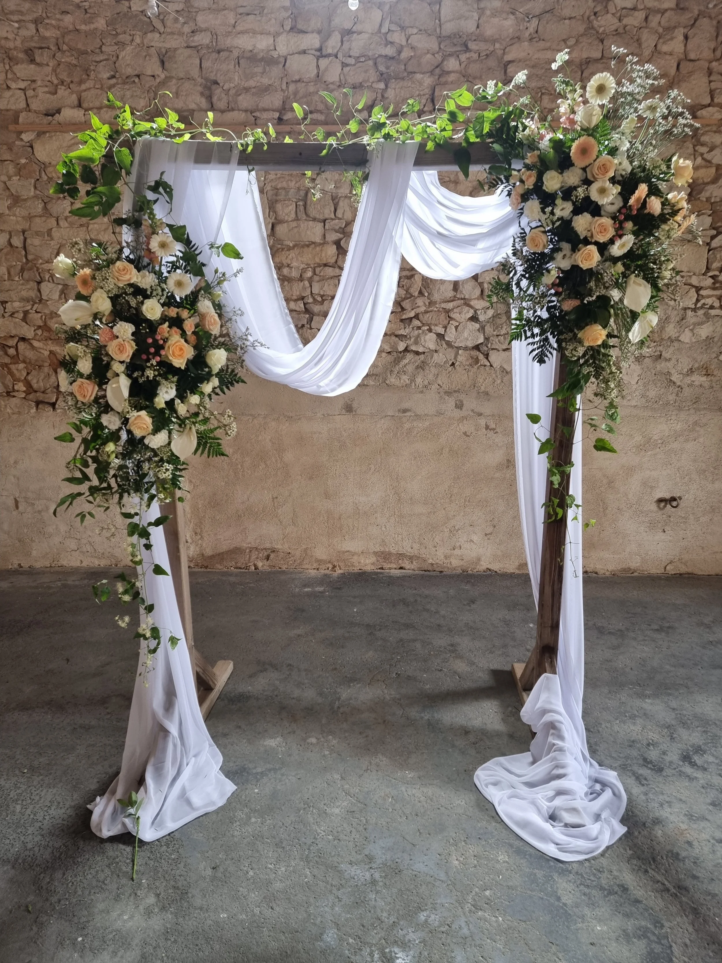wooden structure creating a backdrop for a wedding at a chateau in france with peach and white colored flowers