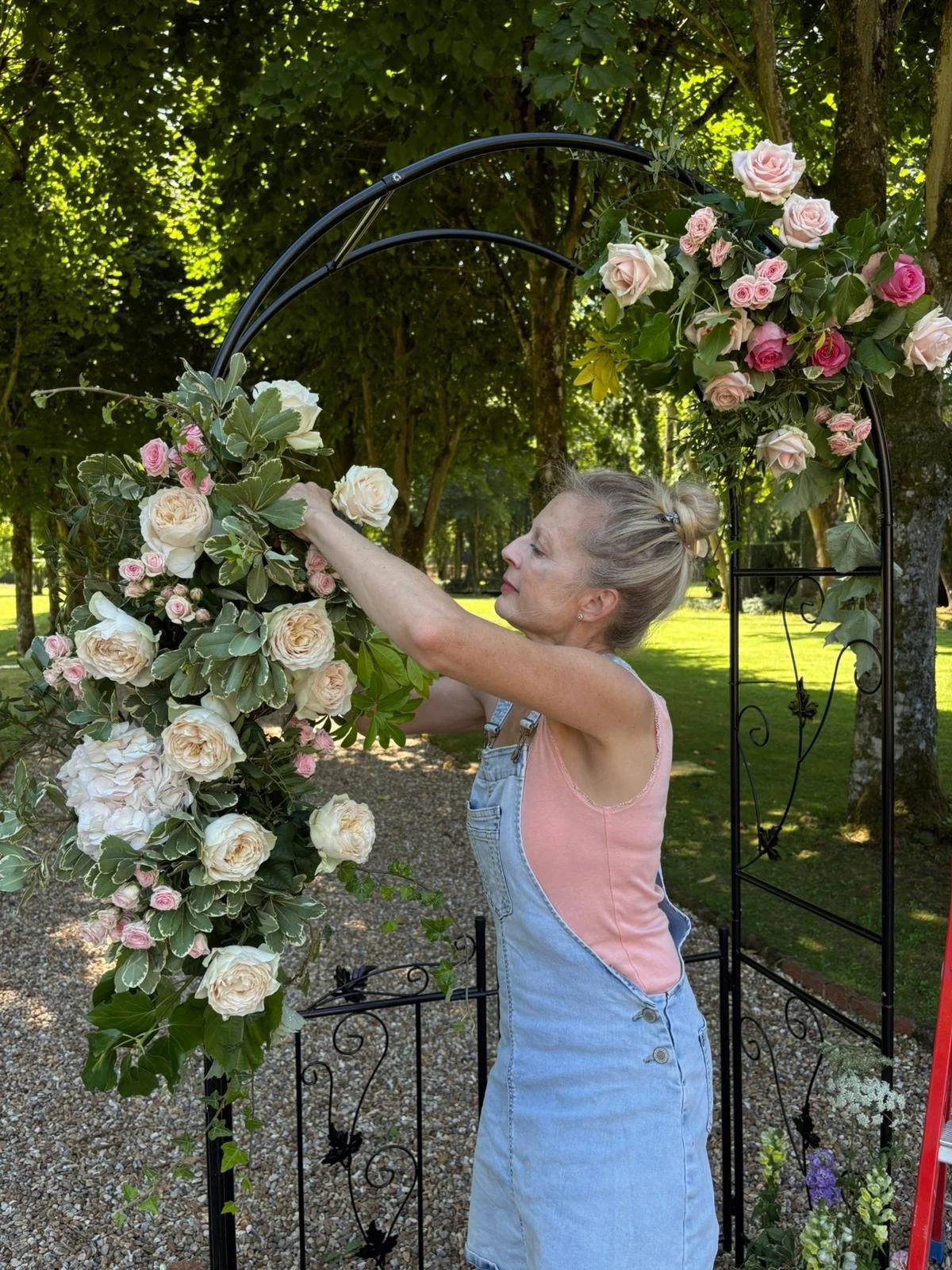 woman arranging wedding flowers in a floral arch for a chateau wedding in france