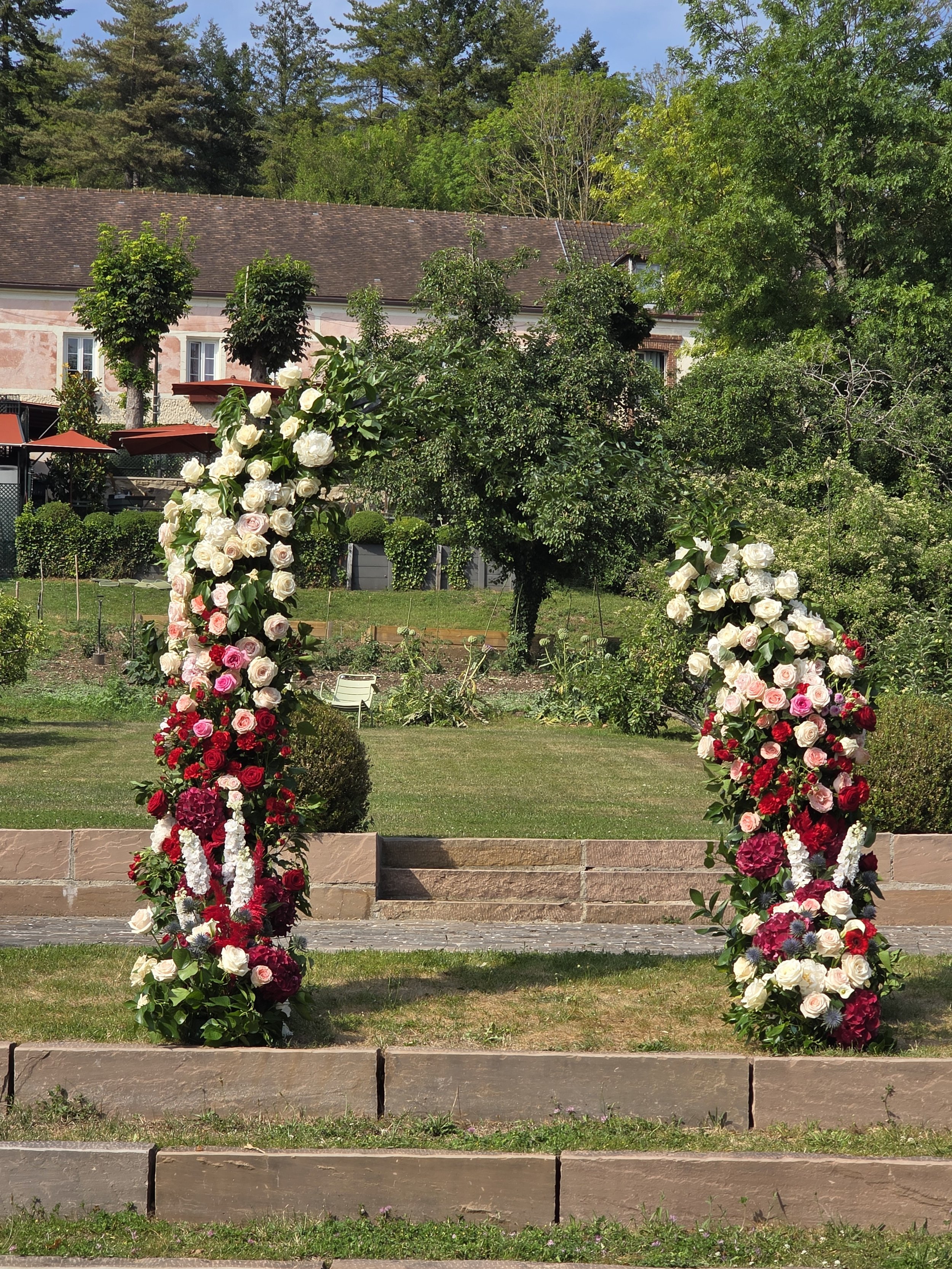 Color palette of white, pink and red as a floral  arch for the wedding ceremony in France