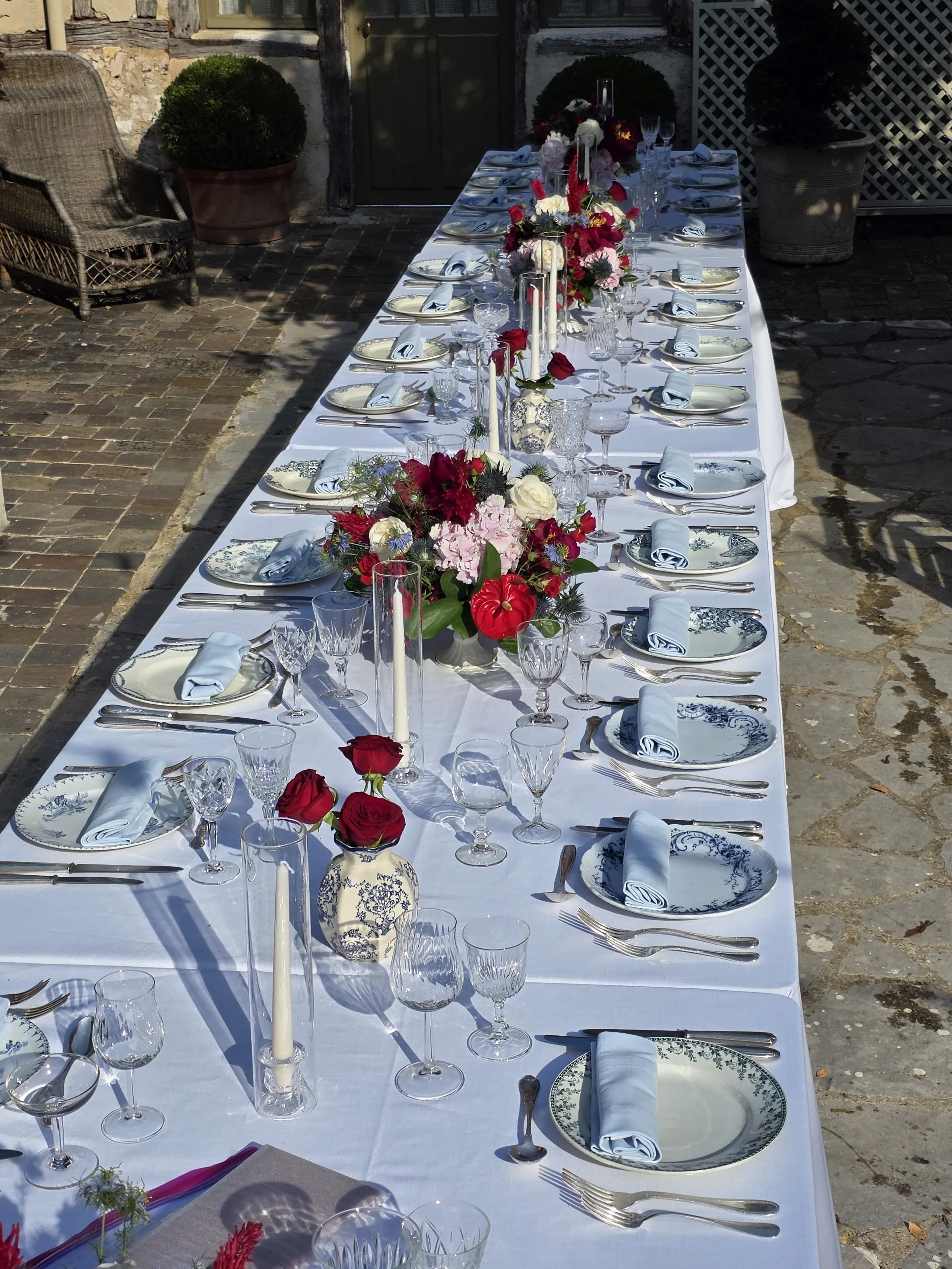Dinner was served on French blue chinaware and bouquets lined the table with a small chinaware blue and white vase with large red roses.