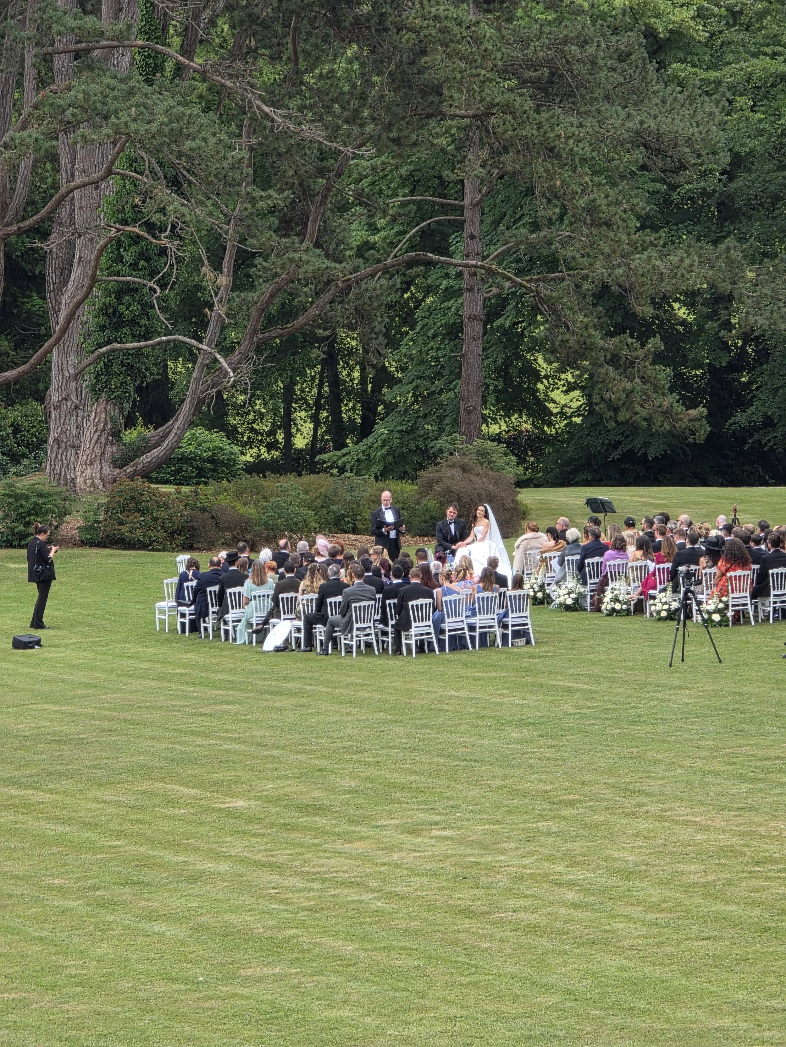 A wide open space for a wedding ceremony with guests and trees