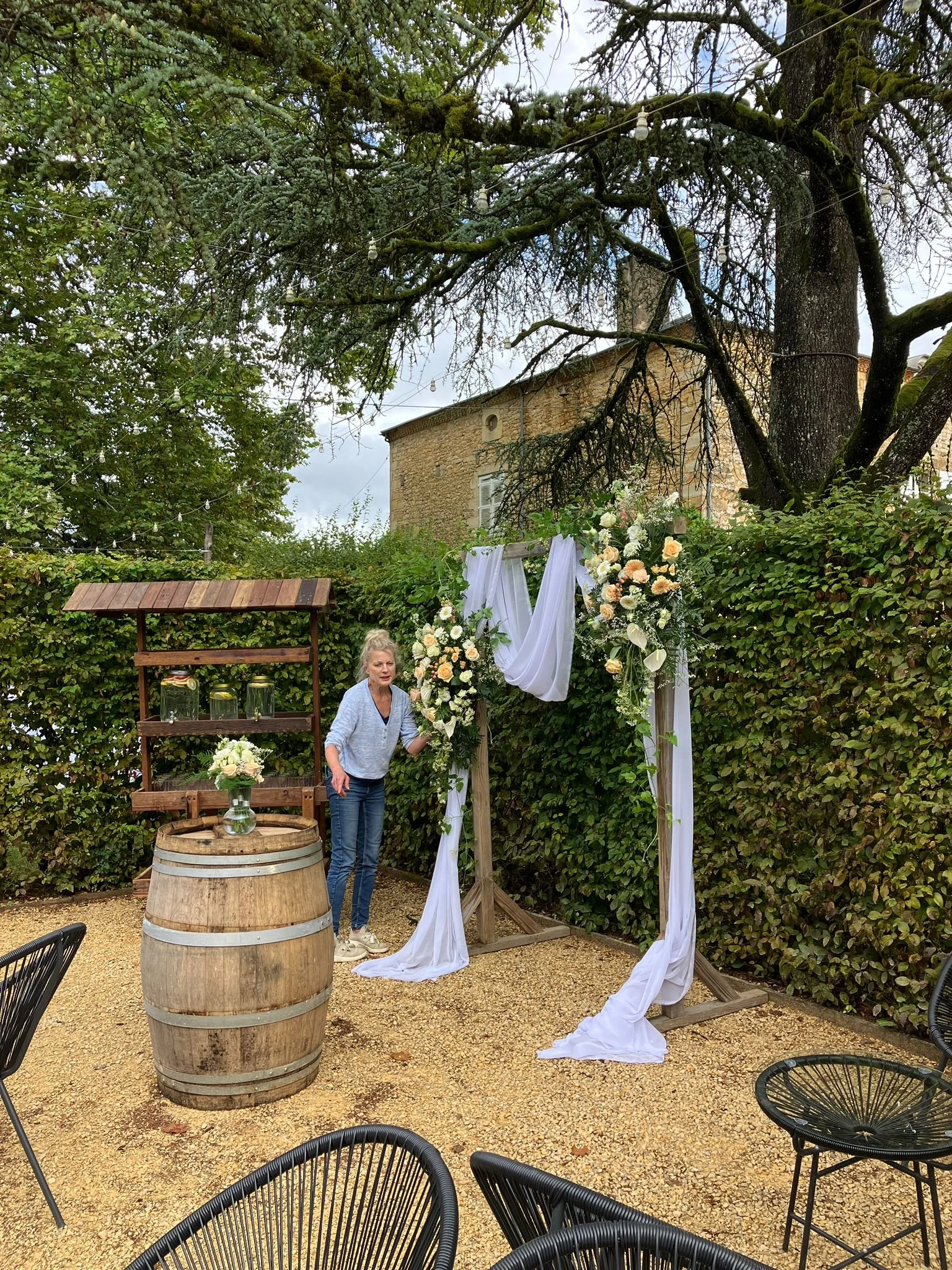 a wedding florist arranges flowers repurposing from ceremony to the outdoor bar area in france.