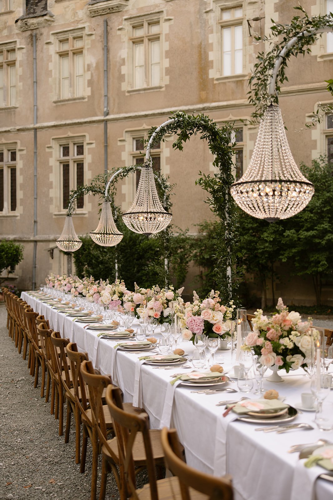 Wedding table at Chateau Allure du Lac for a wedding in France in June with hanging chandeliers and beautiful summer floral arrangements with the chateau in the background