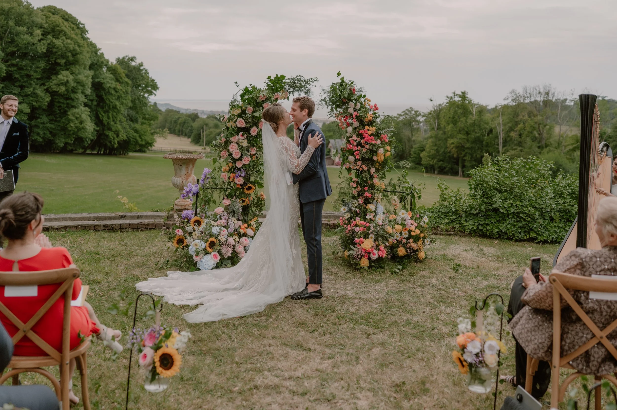 A couple getting married stand in front of a floral arch inspired like a real garden in france