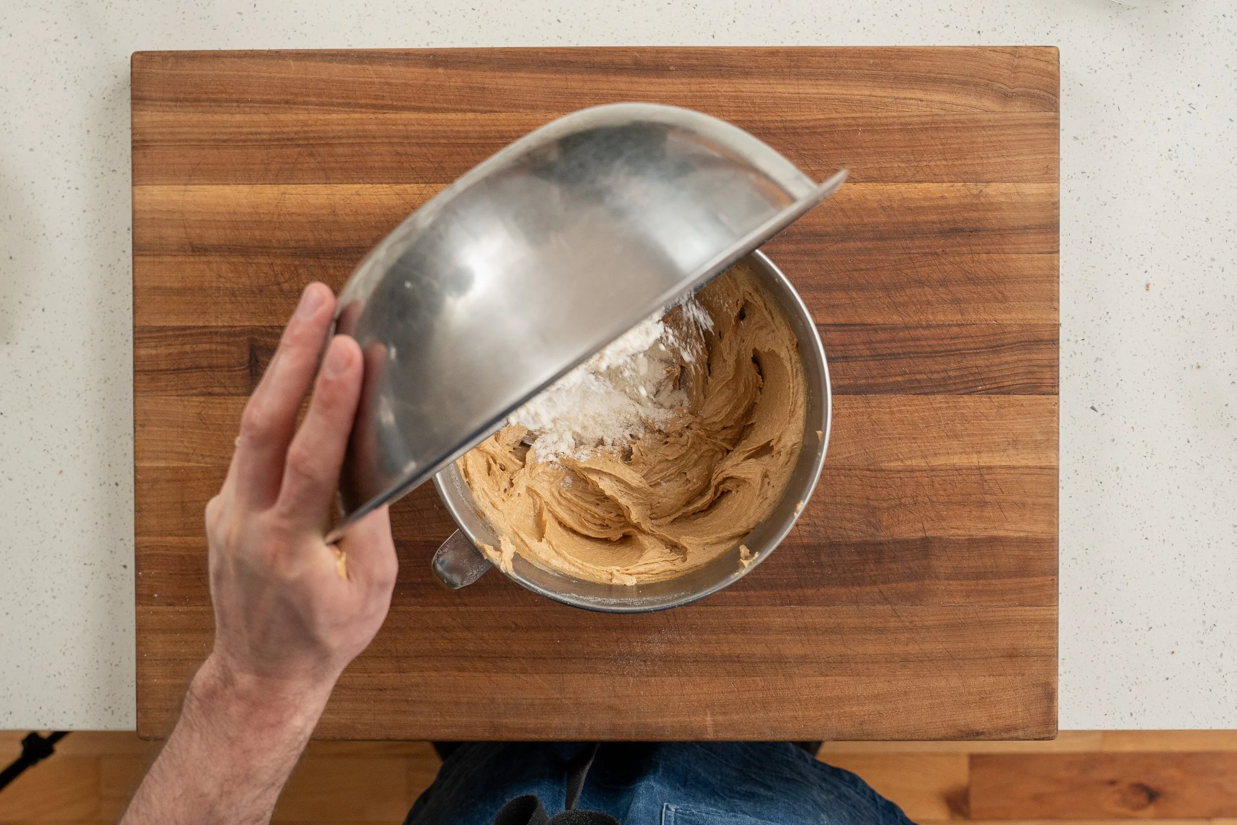 adding dry ingredients into creamed wet ingredients for peanut butter cookies