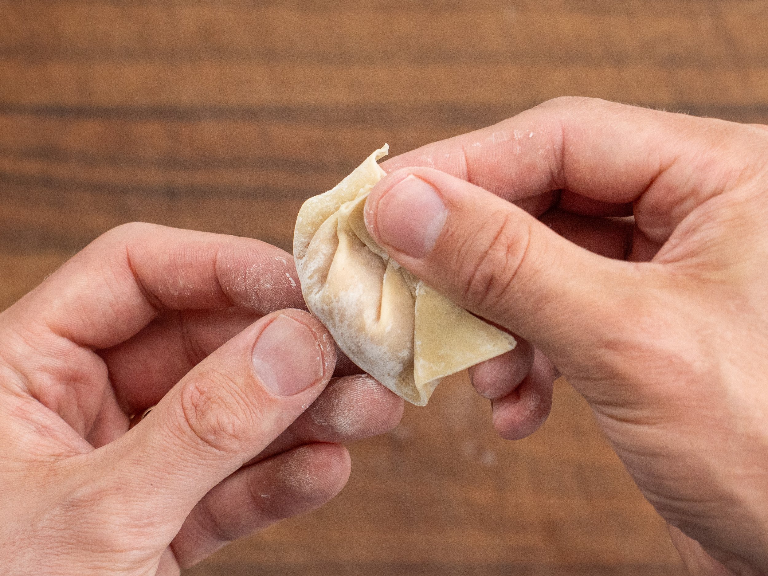 hands folding a wonton