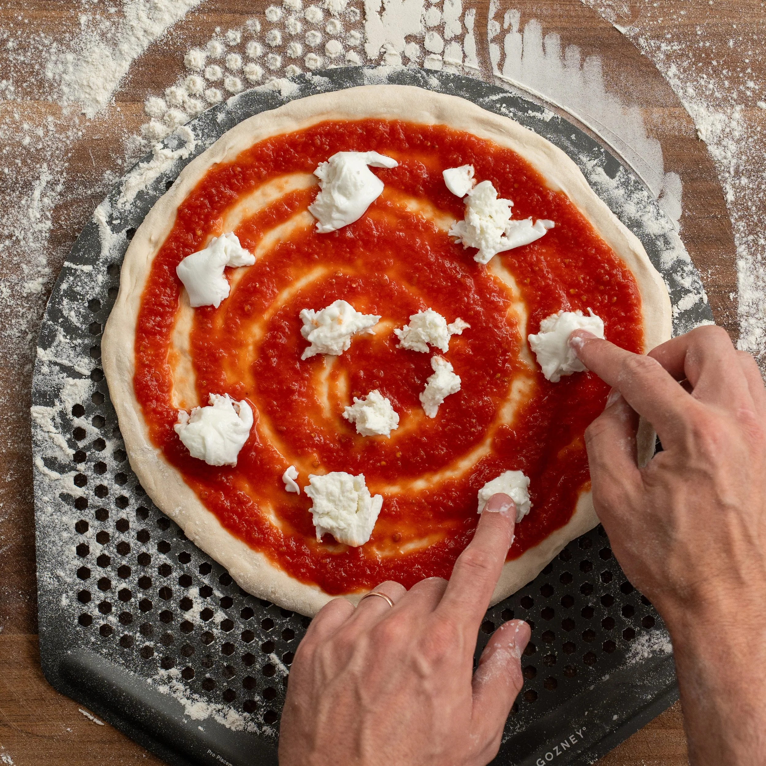 adding fresh mozzarella to pizza dough