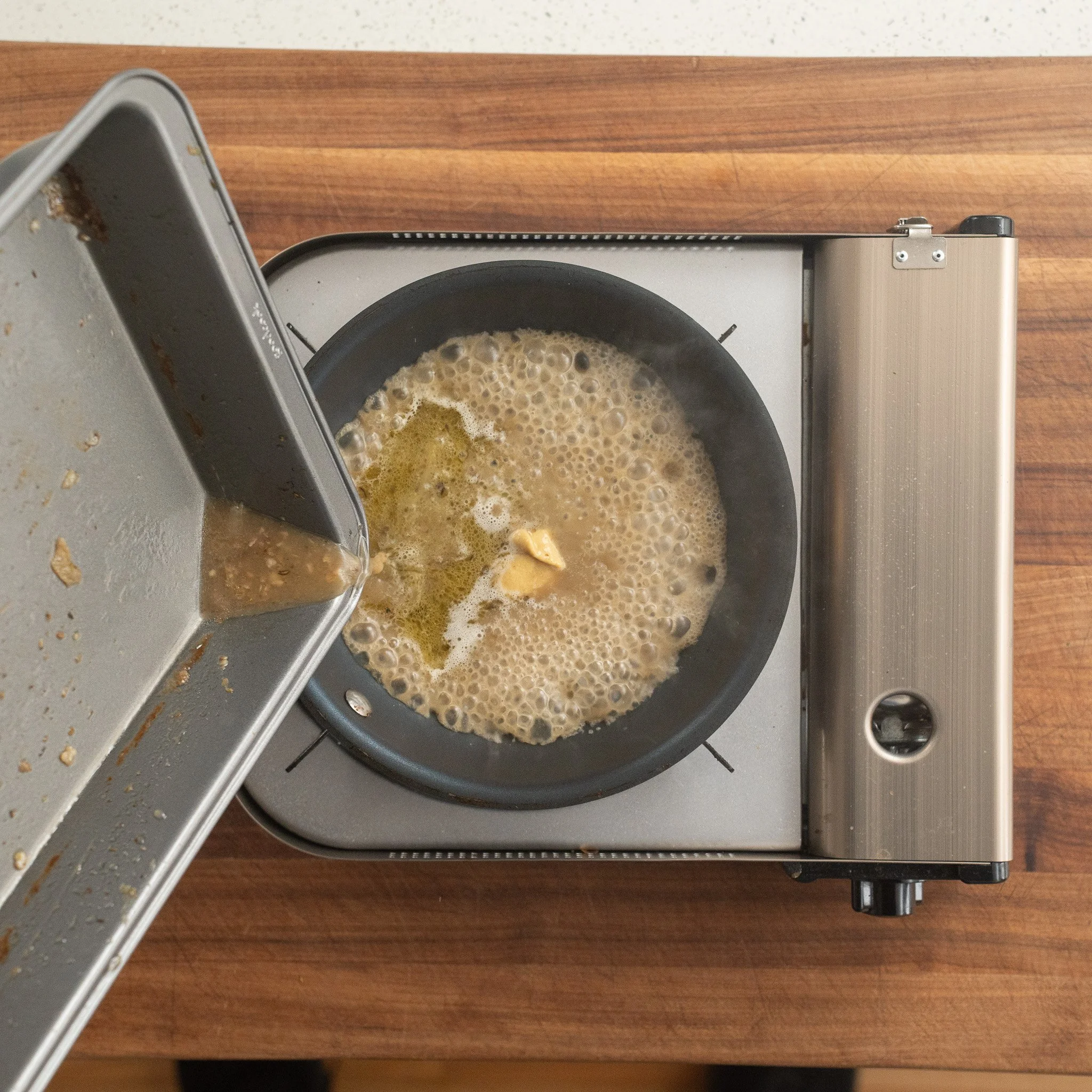 pouring roasting chicken juices into a pan with dijon mustard
