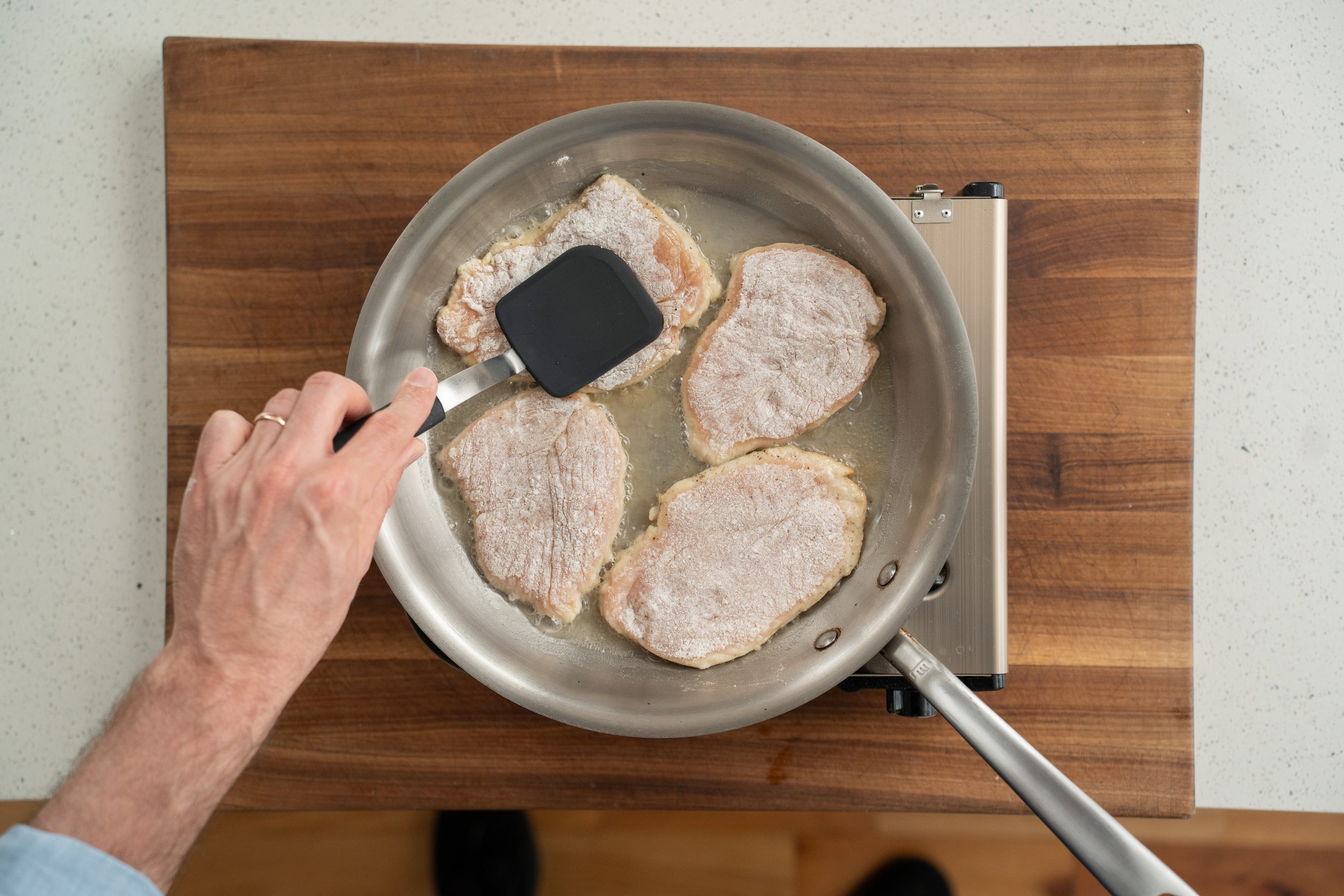 pressing down on chicken breast with a spatula while searing