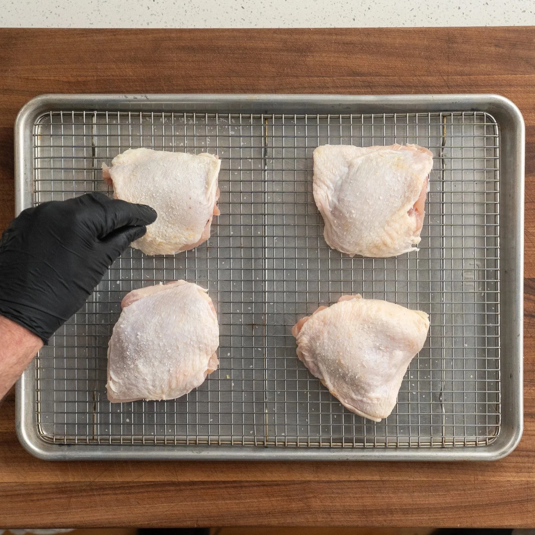 salting chicken thighs on a sheet pan
